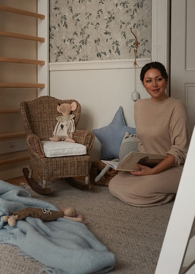 Gemütliche Kinderecke mit Rattanschaukelstuhl und Plüschtieren auf grauem Teppich