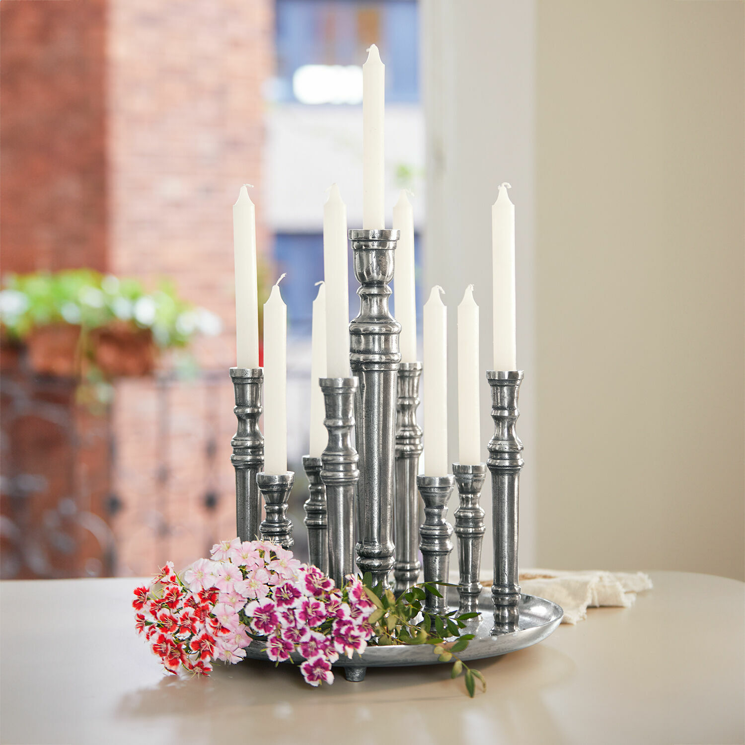 Kerzenhalter Calcot Metall-Kerzenhalter mit weißen Kerzen und bunten Blumen auf hellem Tisch im Raum