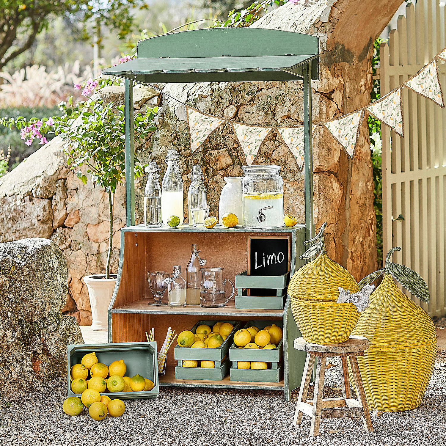 Limonadenstand Éclairon Grüner Holzstand mit Zitronen und Glasflaschen für Limonade im Garten