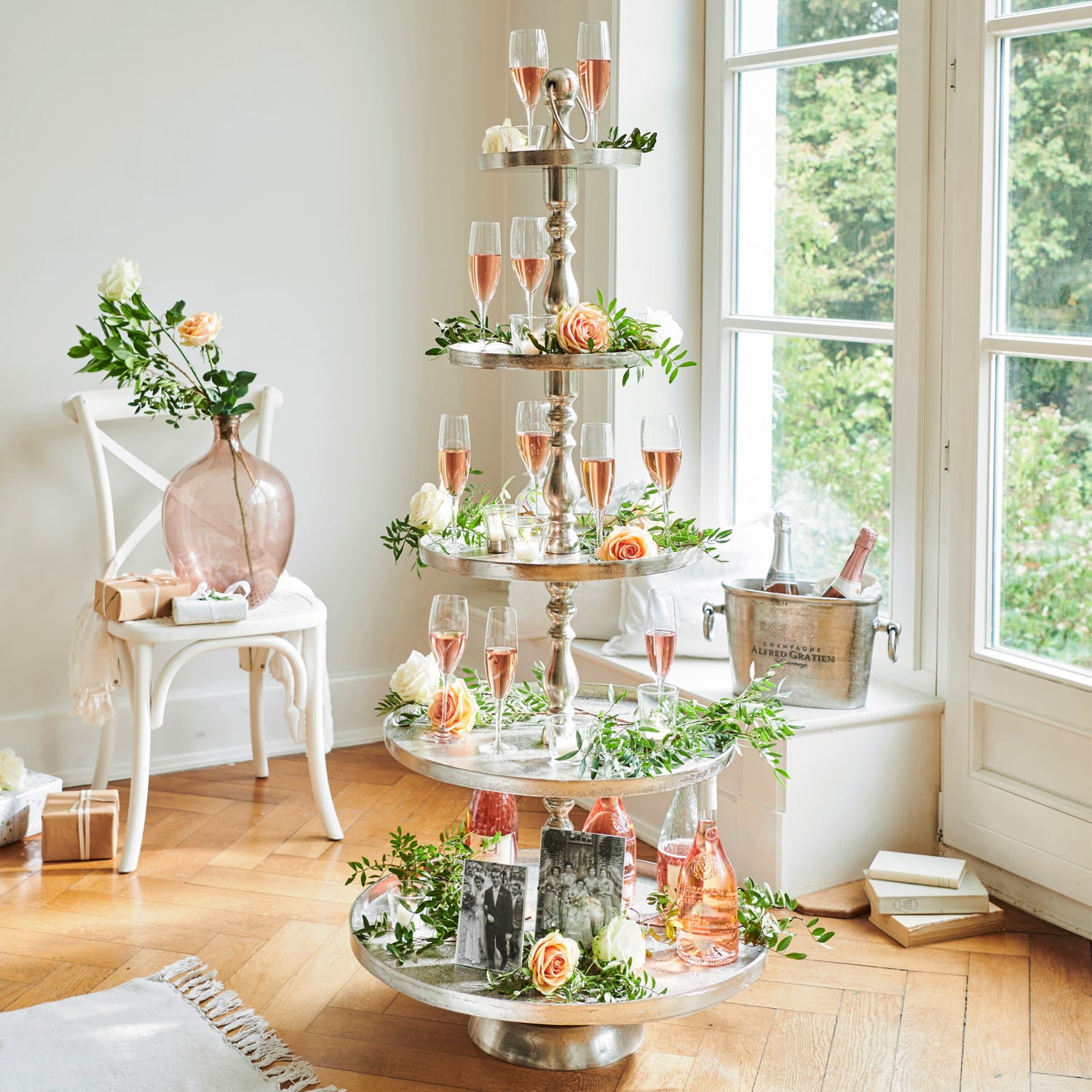 Vierstöckiges Metall-Etagere mit Roséwein und Blumenarrangements in hellem Raum