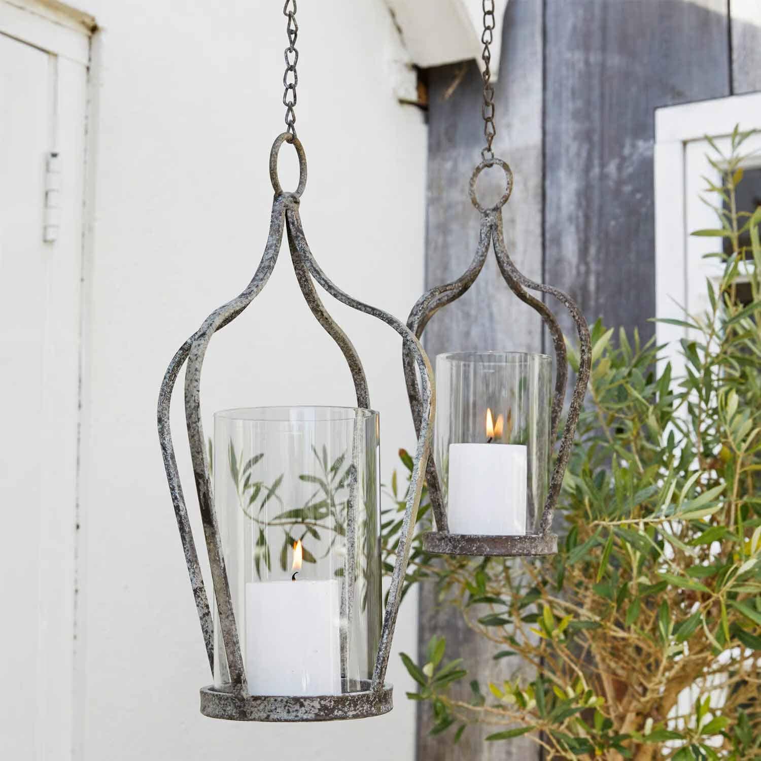 Hängende Metalllaternen im Vintage-Stil mit weißen Kerzen und Glasschutz für Gartendekoration