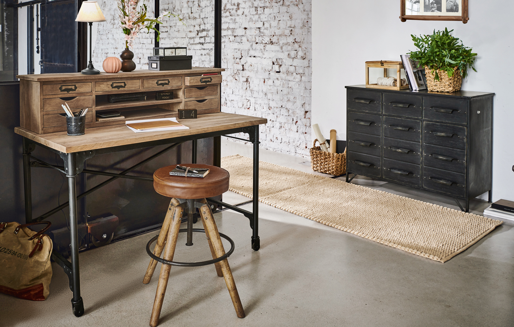 Industrieller Schreibtisch aus Holz und Metall mit vielen Schubladen und vintage Lederhocker im Raum