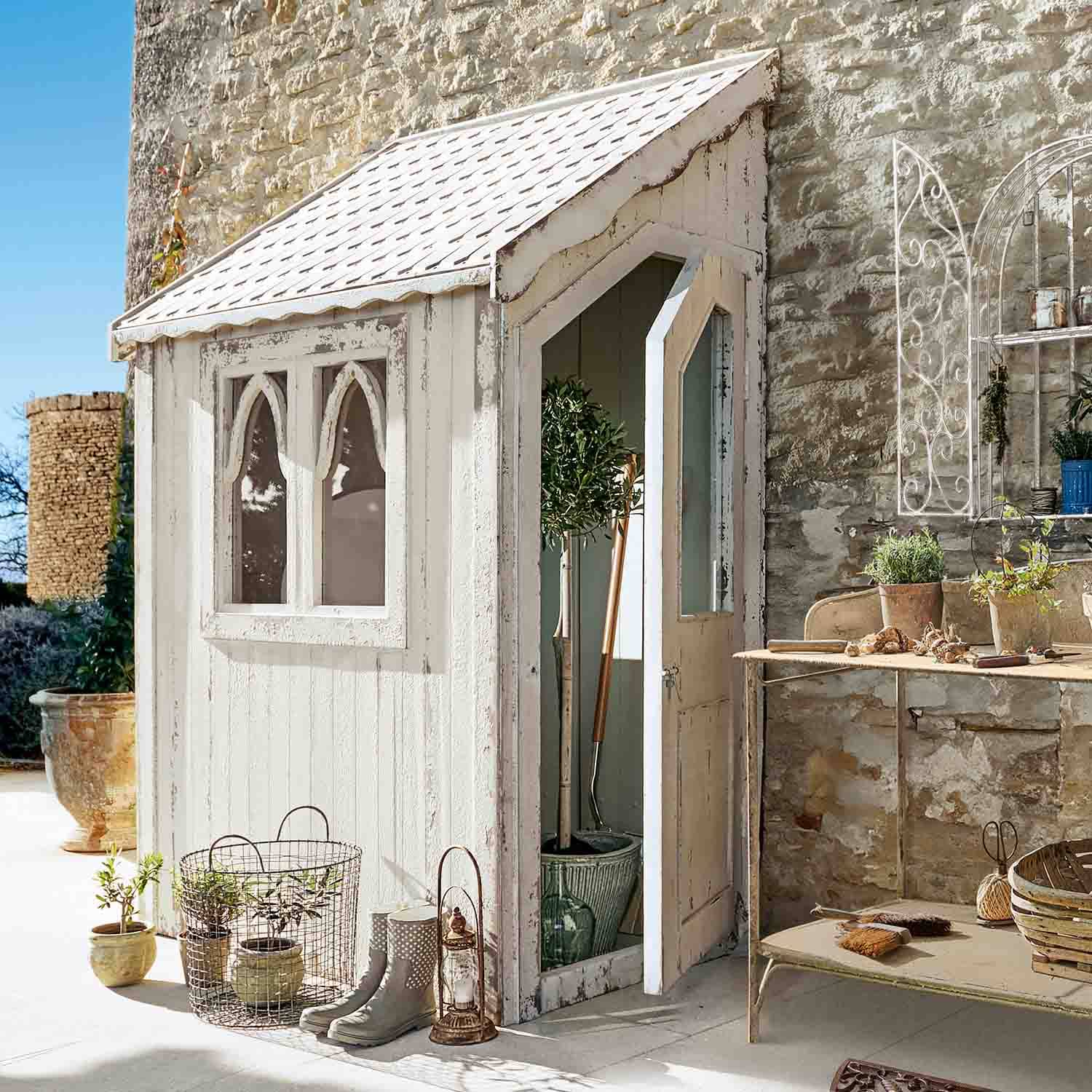 Weißes Holz-Gartenhaus mit Fenstern und offener Tür, Gartendekoration und Werkzeuge