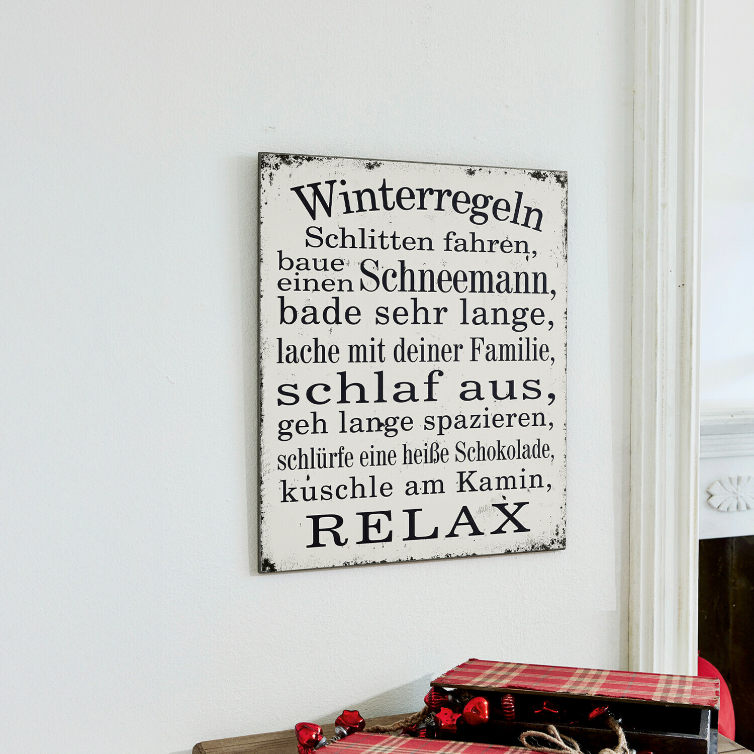 Dekoboard Winterregeln Weißes Metallschild mit schwarzem Winterregeln-Text und brennenden roten Kerzen im Kerzenhalter