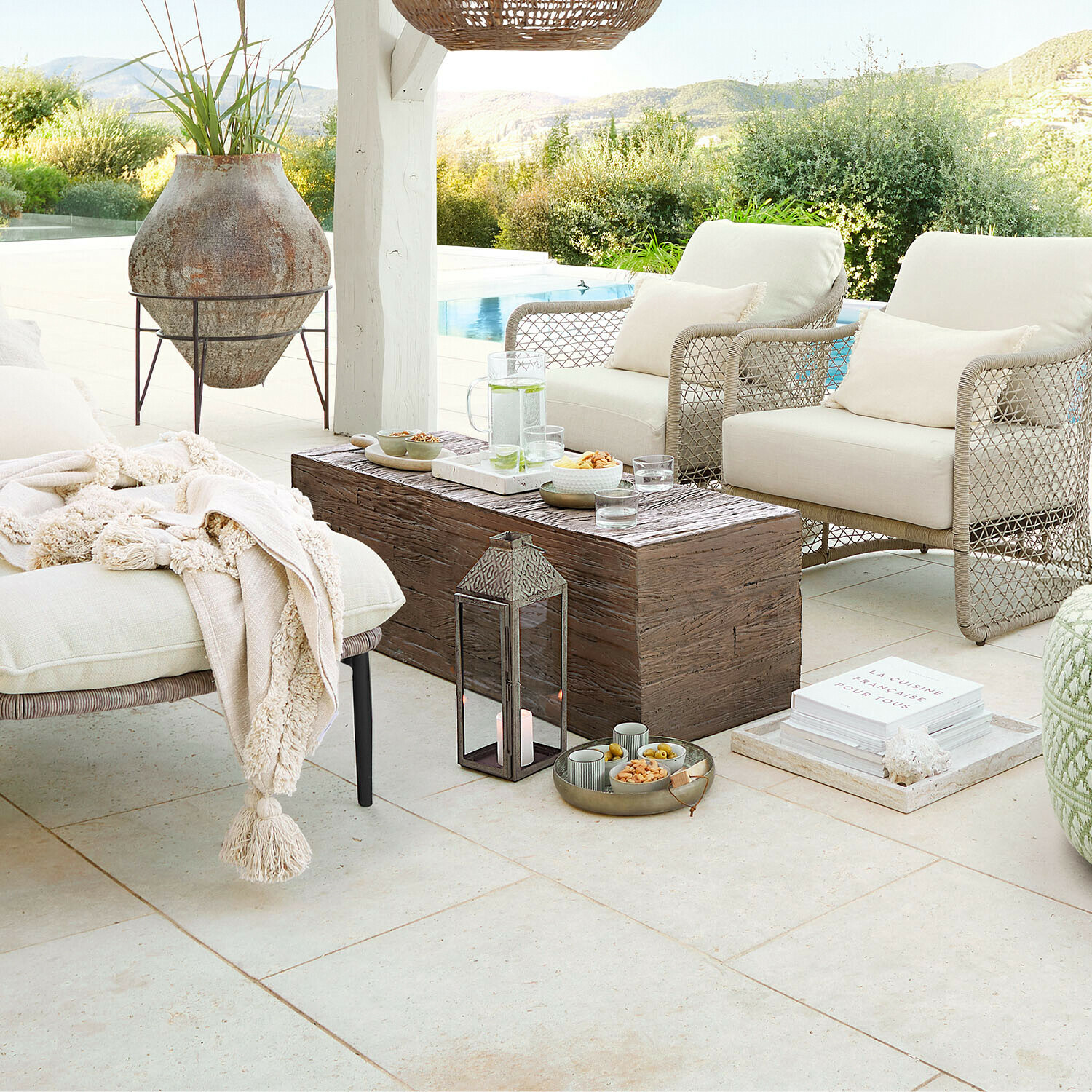 Gemütliche Gartenmöbel mit beigen Polstern und Holztisch auf Terrasse mit Poolblick und Naturkulisse