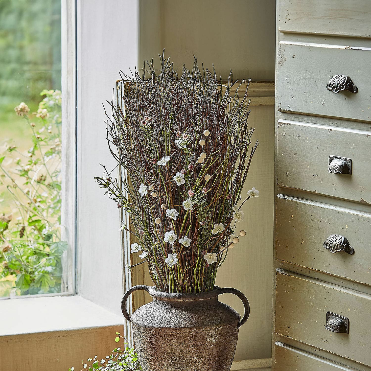Deko-Blumenstrauß Verilo Dekorativer brauner Metallvase mit Zweigen und weißen Blüten auf Fensterbank