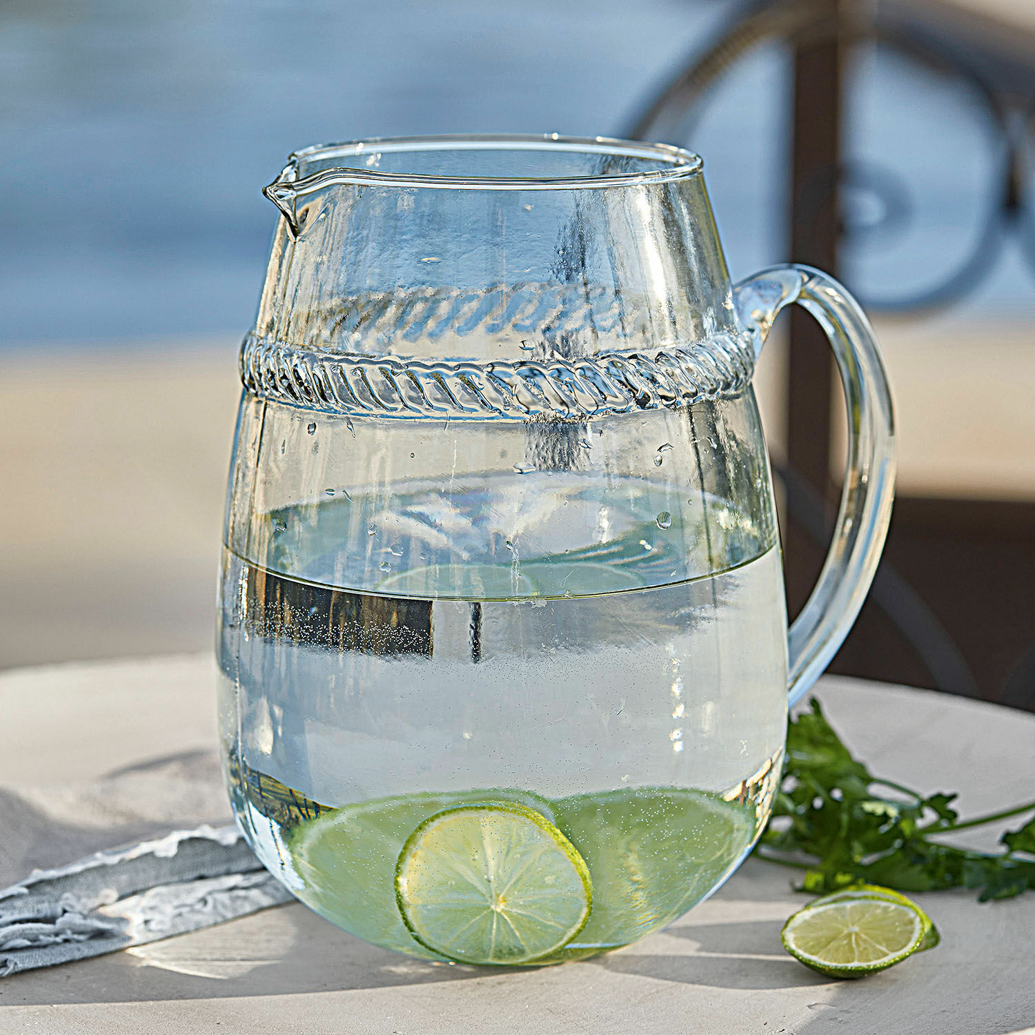 Krug Beiras Glaskrug aus klarem Glas mit Wasser und Limettenscheiben auf Gartentisch