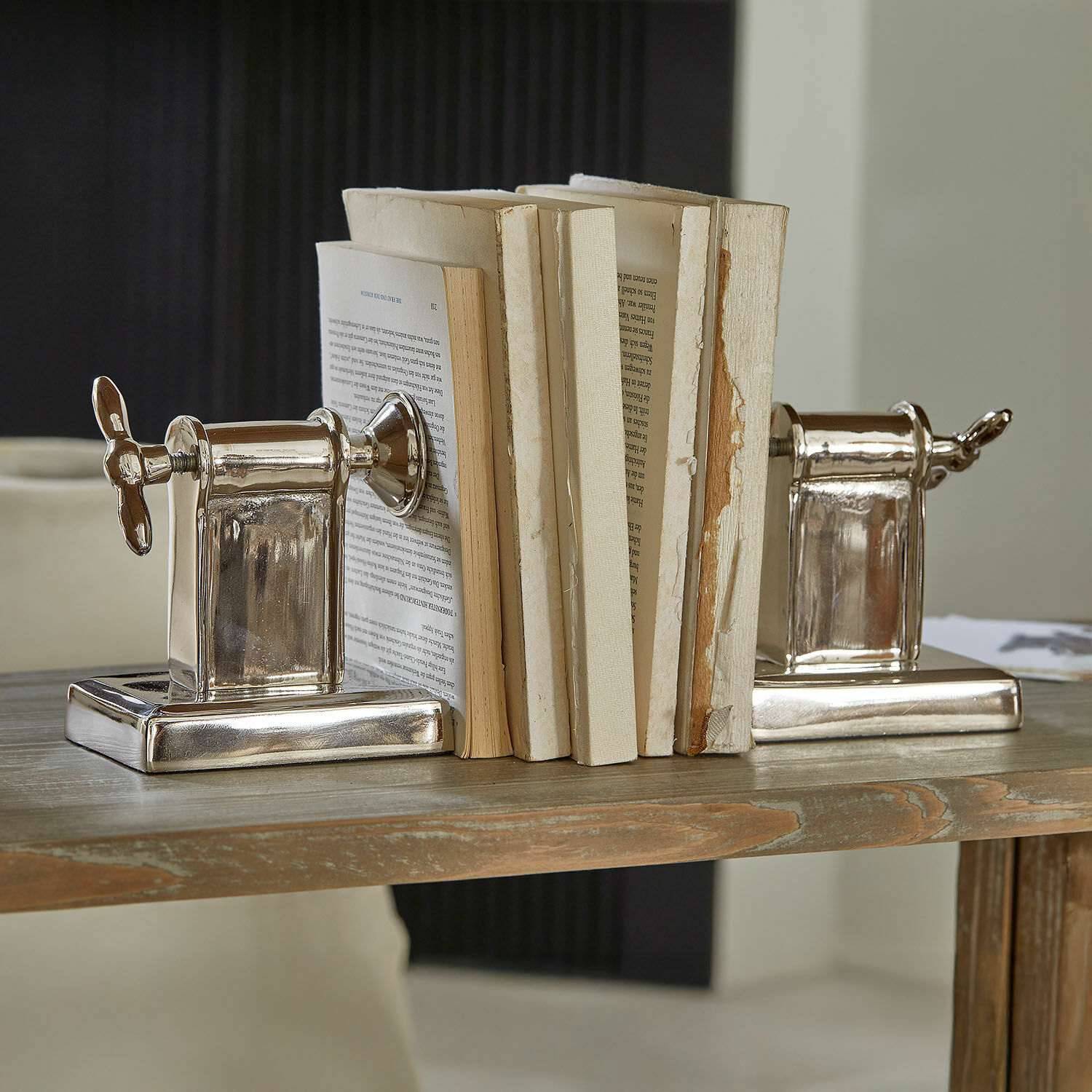 Silberne Buchstützen aus Metall in Schraubenform auf einem Holztisch, Wohnaccessoire