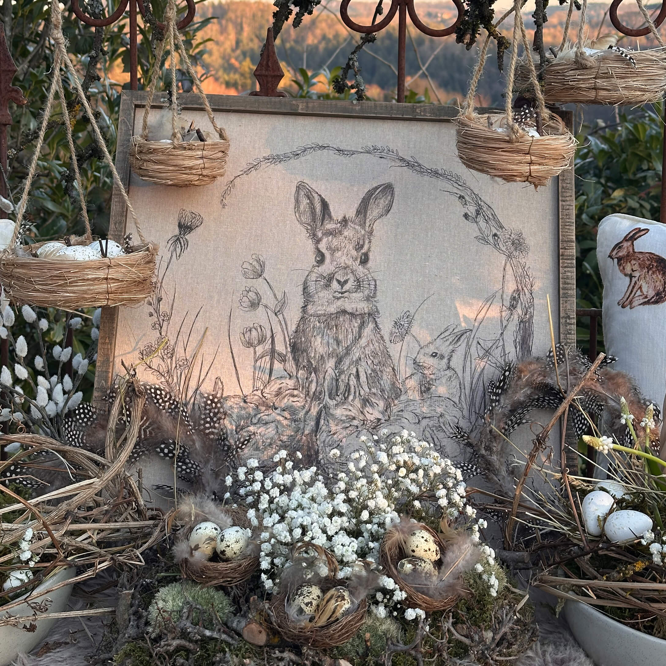 Natürliche Osterdekoration mit Nestern, Federn und Hasenzeichnung auf Leinwand