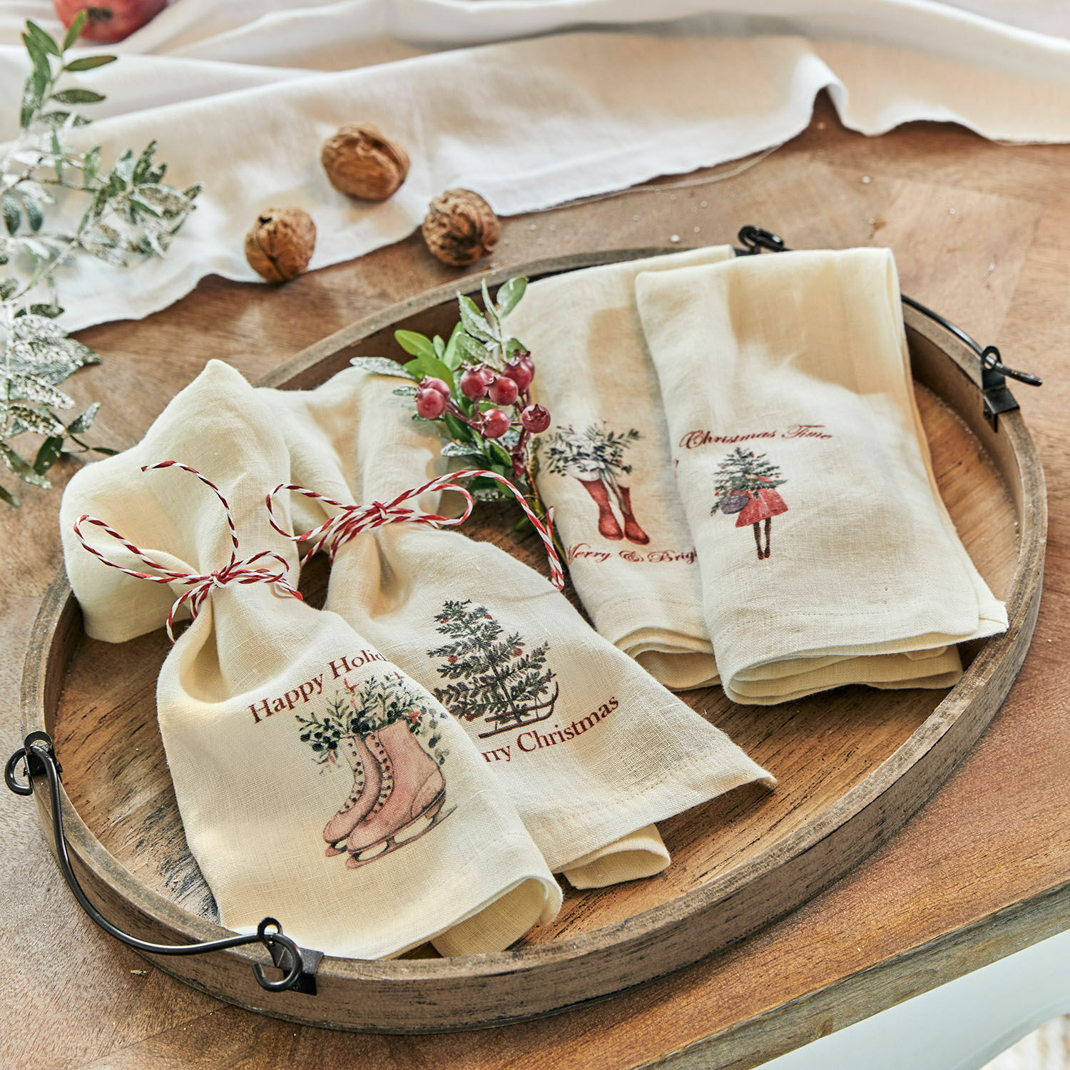 Serviette 4er Set Merry & Bright Leinen-Geschirrtücher in Creme mit Weihnachtsmotiven und rotem Band auf rustikalem Holztablett