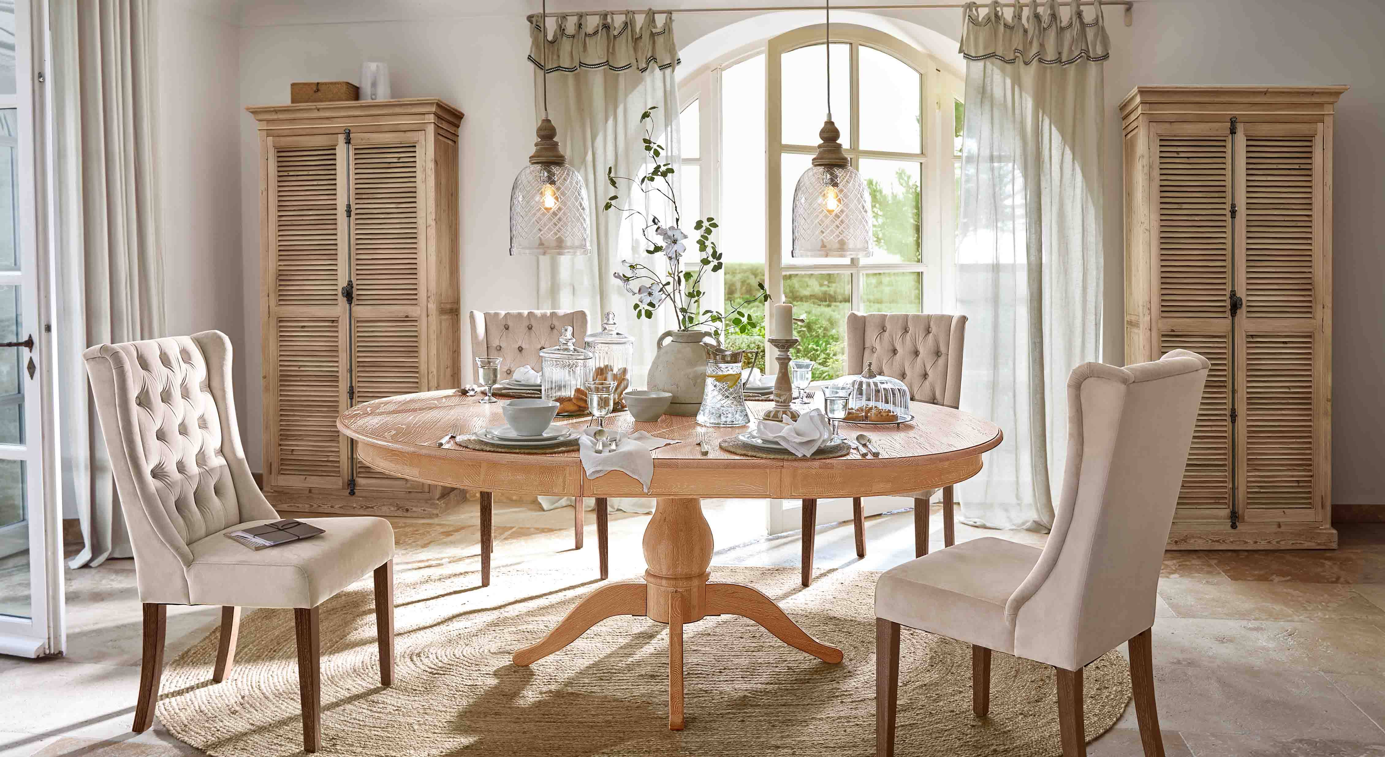 Esszimmer mit runder Holz-Tisch und beige gepolsterten Stühlen im klassischen Landhausstil