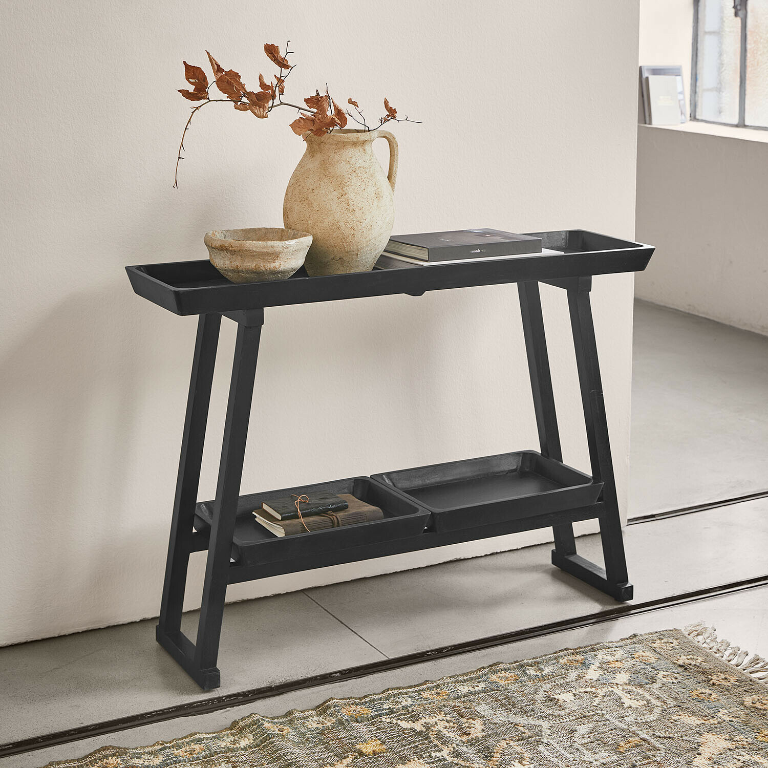 Konsole Ivywood Schwarzer Holzbeistelltisch mit Ablagen, Keramikvase und Büchern in minimalistischem Raum