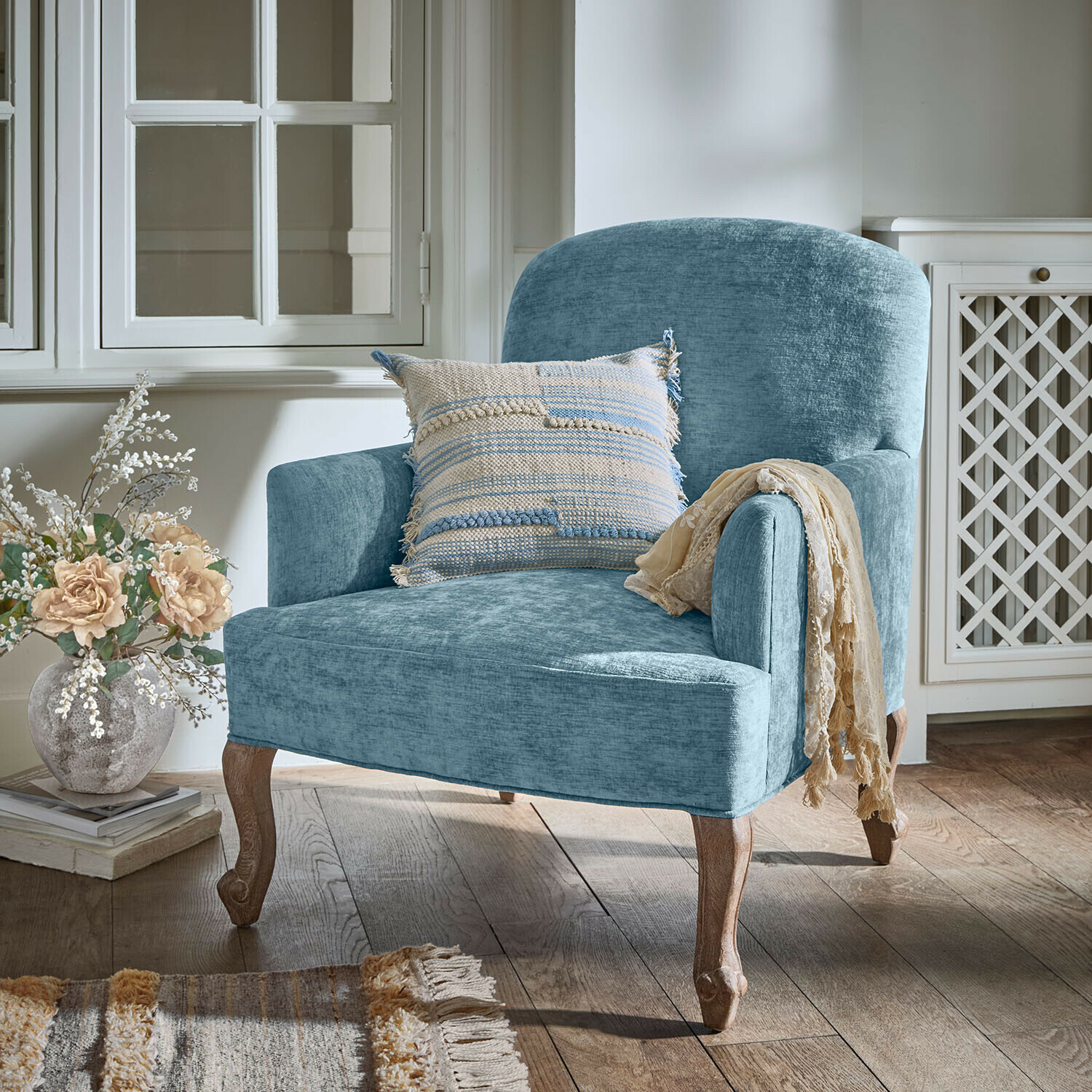 Blauer Polsterstuhl mit Holzbeinen und dekorativem Kissen in gemütlichem Wohnraum