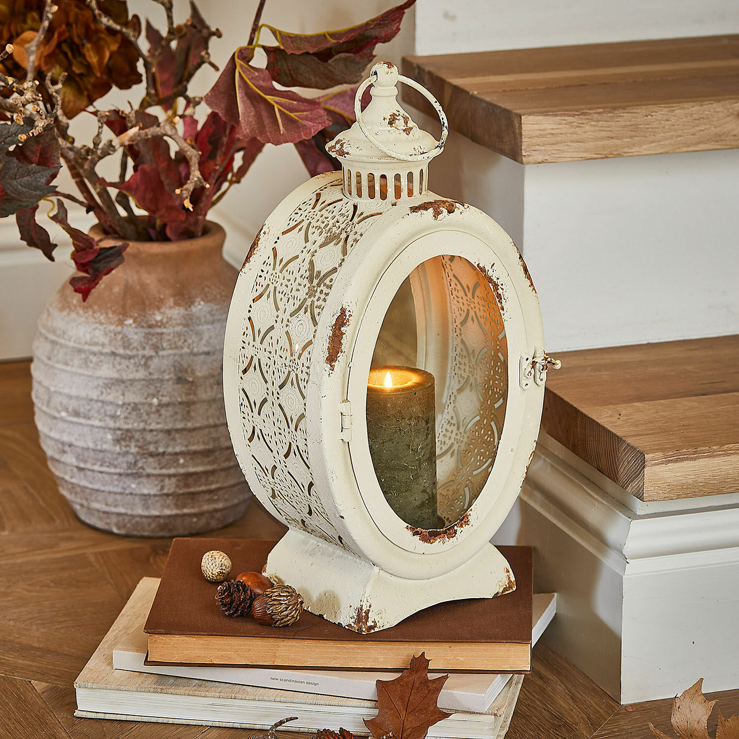 Laterne Sublimelle Vintage Metalllaterne in Creme mit brennender Kerze und herbstlicher Dekoration auf Büchern