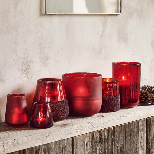 Set aus roten Glaswindlichtern auf Holzregal, dekorative Wohnraumbeleuchtung