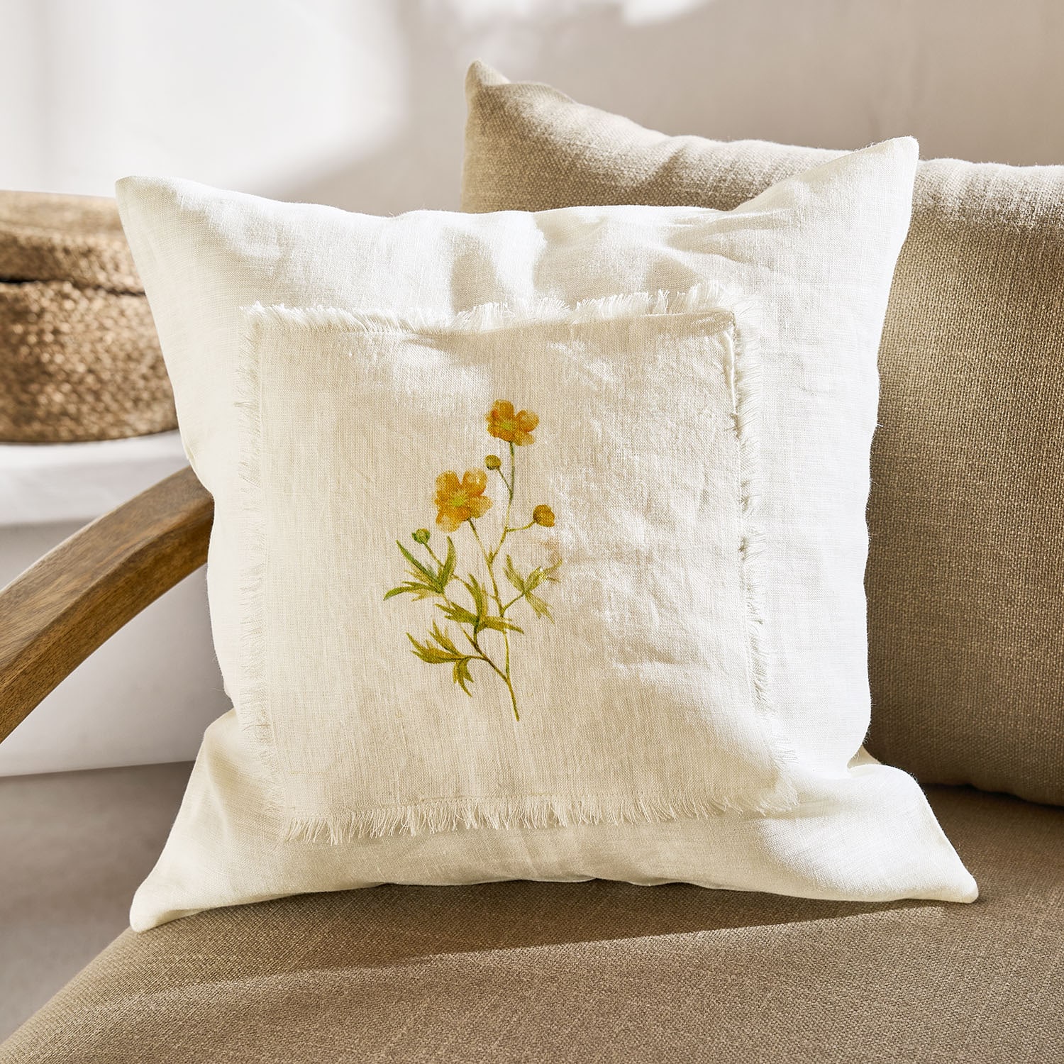 Dekoratives Kissen aus cremefarbenem Leinen mit gelbem Blumenmotiv und Fransenrand