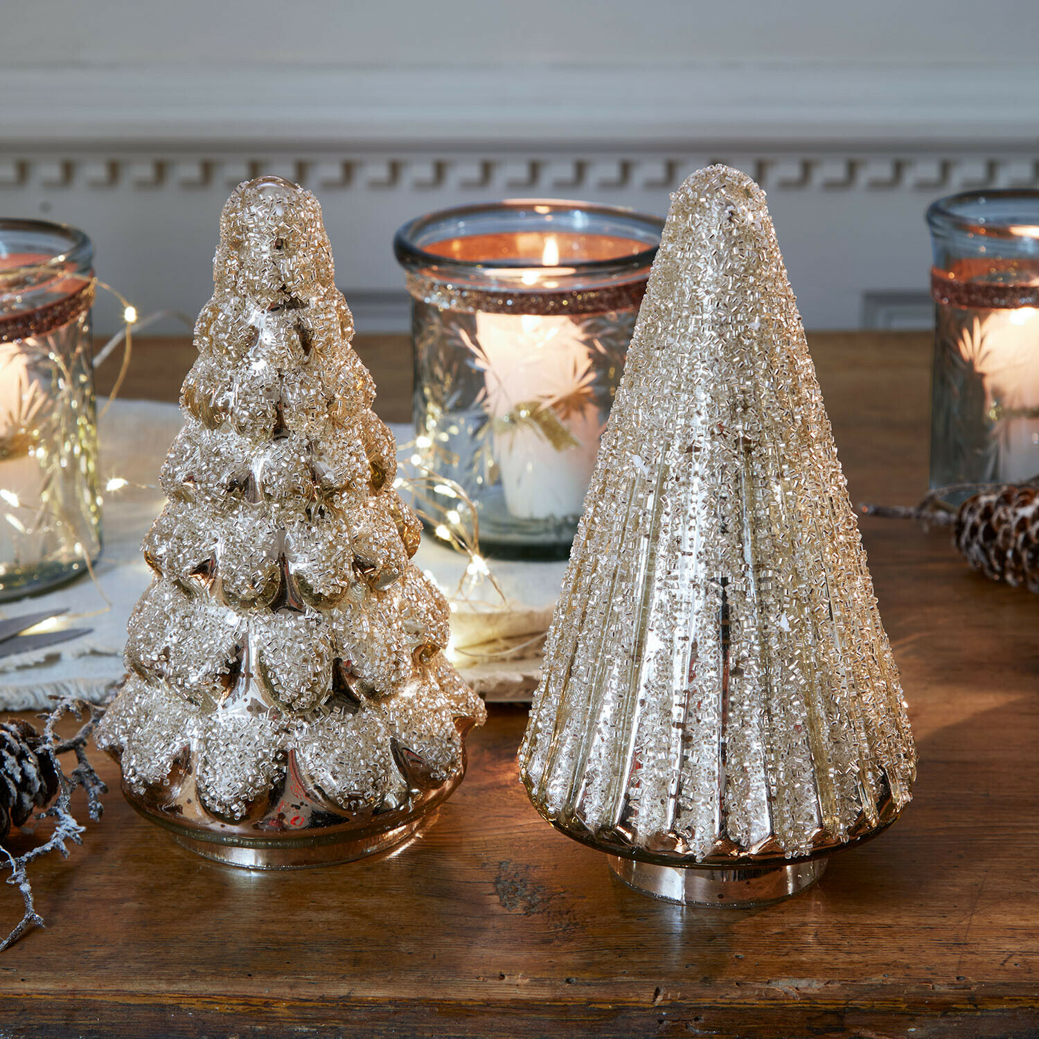 Deko-Baum 2er Set Domélys Zwei dekorative goldene Glas-Weihnachtsbäume mit Struktur auf Holztisch mit Laternen und Kerzenlicht