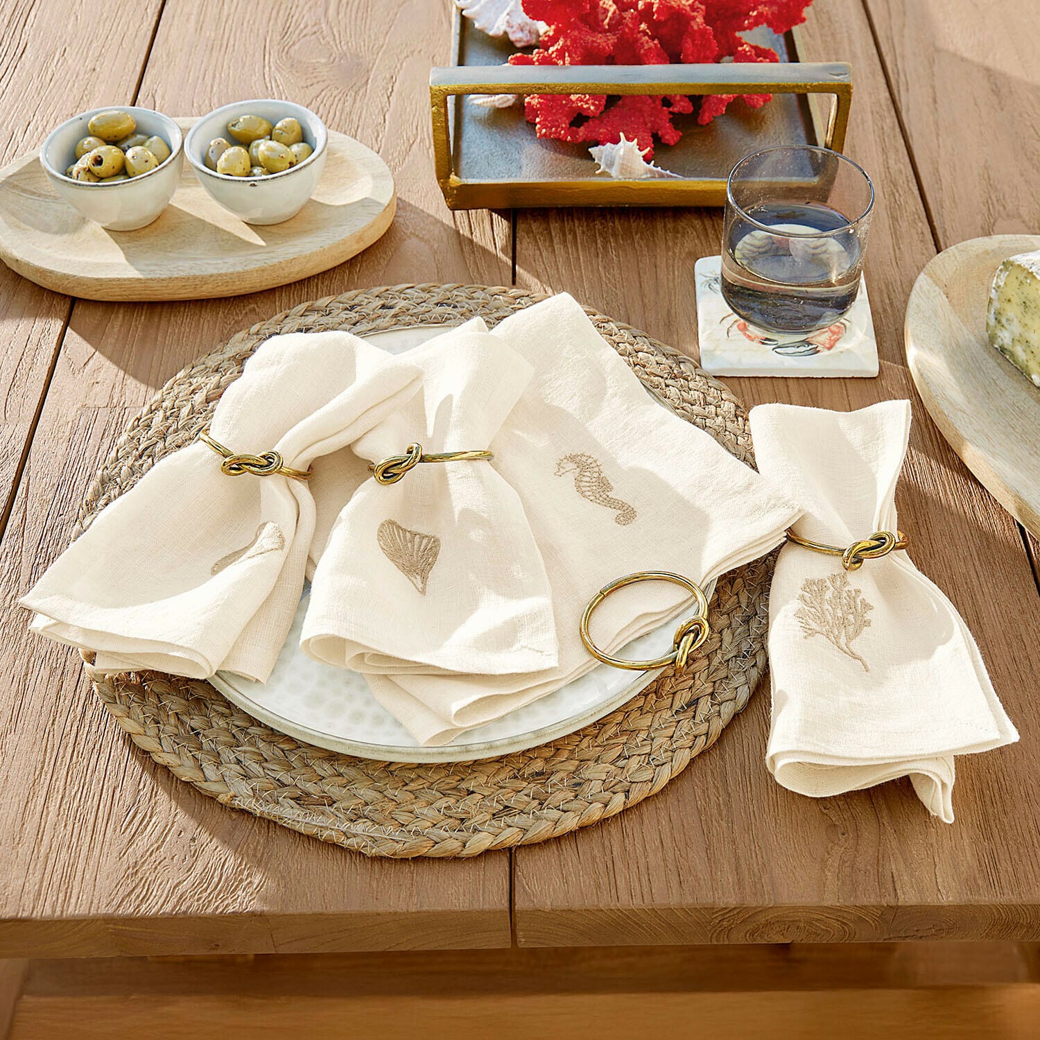 Serviette 4er Set Celorin Leinenservietten in Creme mit maritimen Motiven und goldenen Ringen auf Holztisch als Tischdekoration