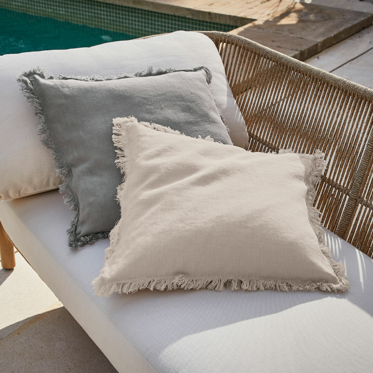 Kissenhülle 2er Set Quebo Leinenkissen in Beige und Grau mit Fransen auf einer Gartenbank neben dem Pool