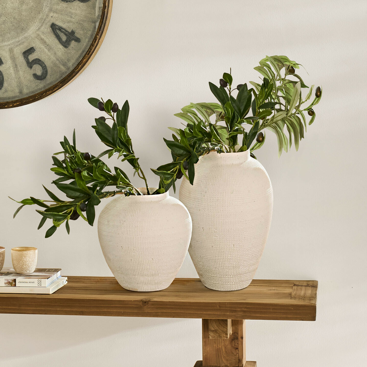 Zwei weiße Keramikvasen mit grünen Blättern auf einem Holztisch, Wohnraumdekoration