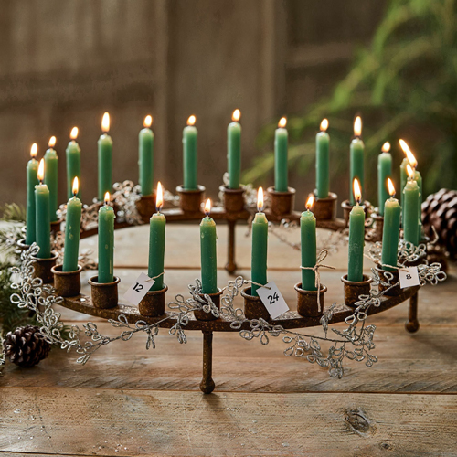 Metall-Adventskranz mit grünen Kerzen und nummerierten Anhängern auf rustikalem Holztisch