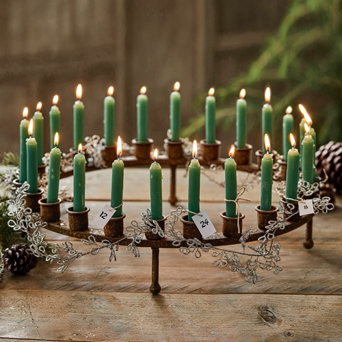 Metall-Adventskranz mit grünen Kerzen und nummerierten Anhängern auf rustikalem Holztisch