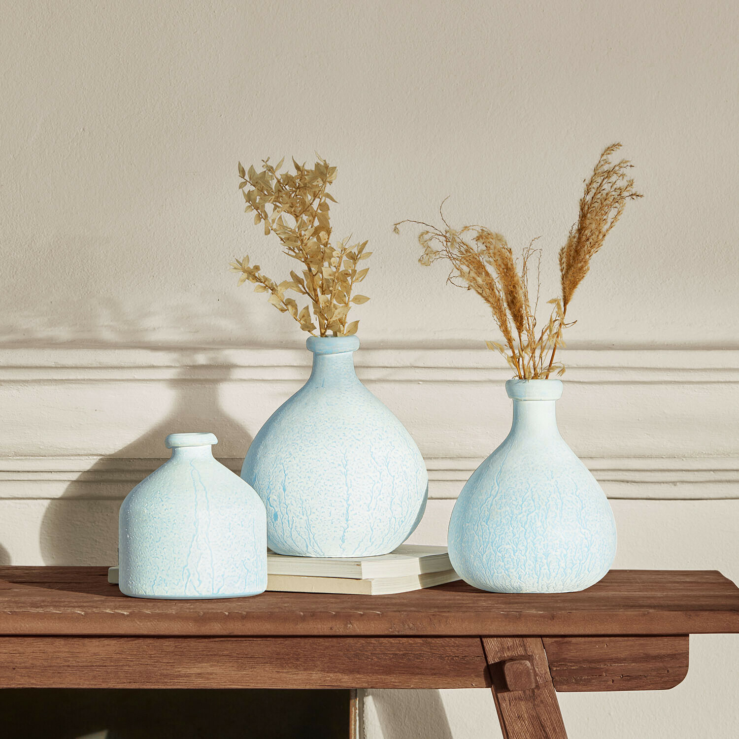 Vase 3er Set Donara Set aus drei hellblauen Keramikvasen mit getrockneten Pflanzen auf Holztisch zur Wohnraumdekoration