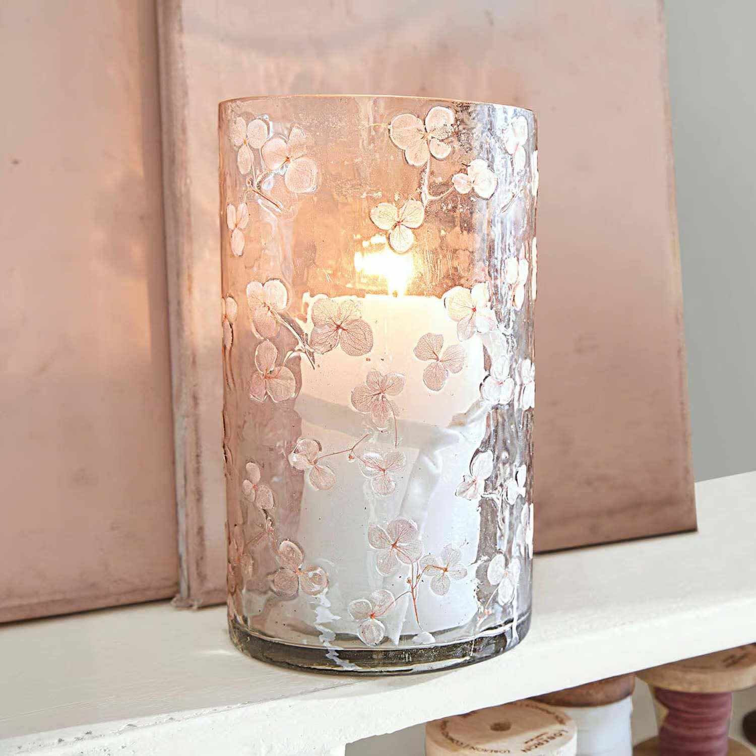Glaswindlicht mit weißen Blumenmustern und brennender Kerze, stilvolle Wohnraumdekoration