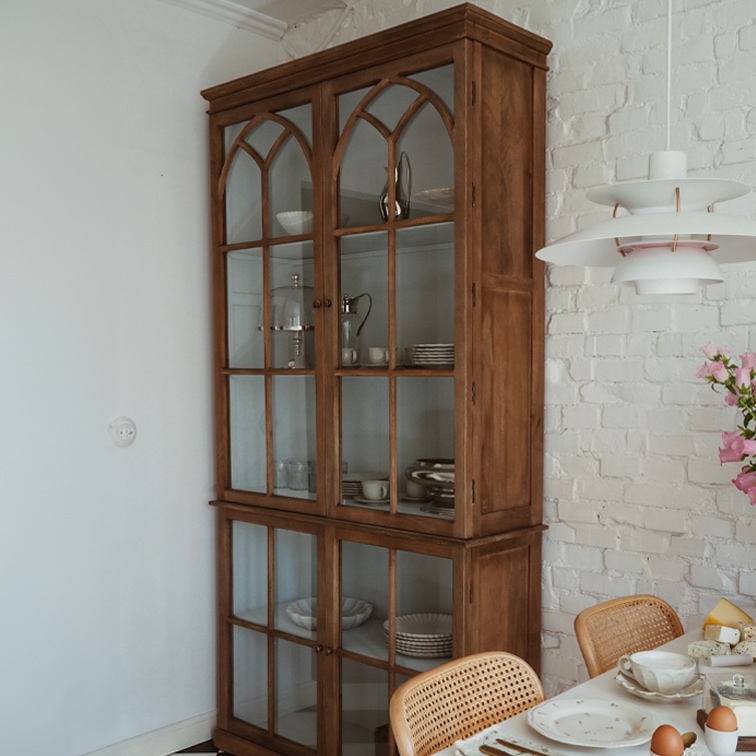 Holzvitrine mit verglasten Türen im Vintage-Stil in einem Esszimmer mit weißer Ziegelwand