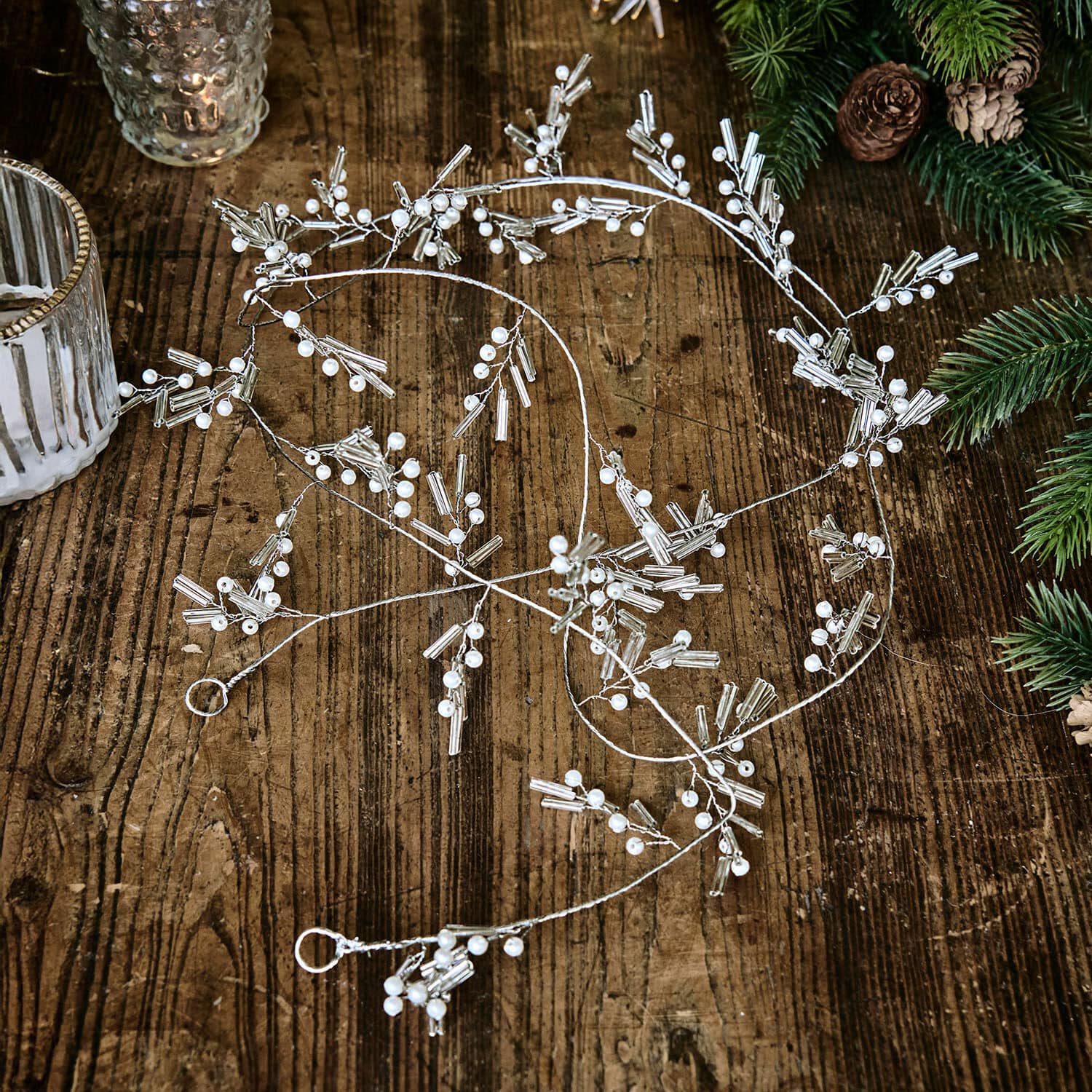Girlande Hybern Feine silberne Dekokette mit weißen Perlen auf Holztisch, festliche Weihnachtsdekoration