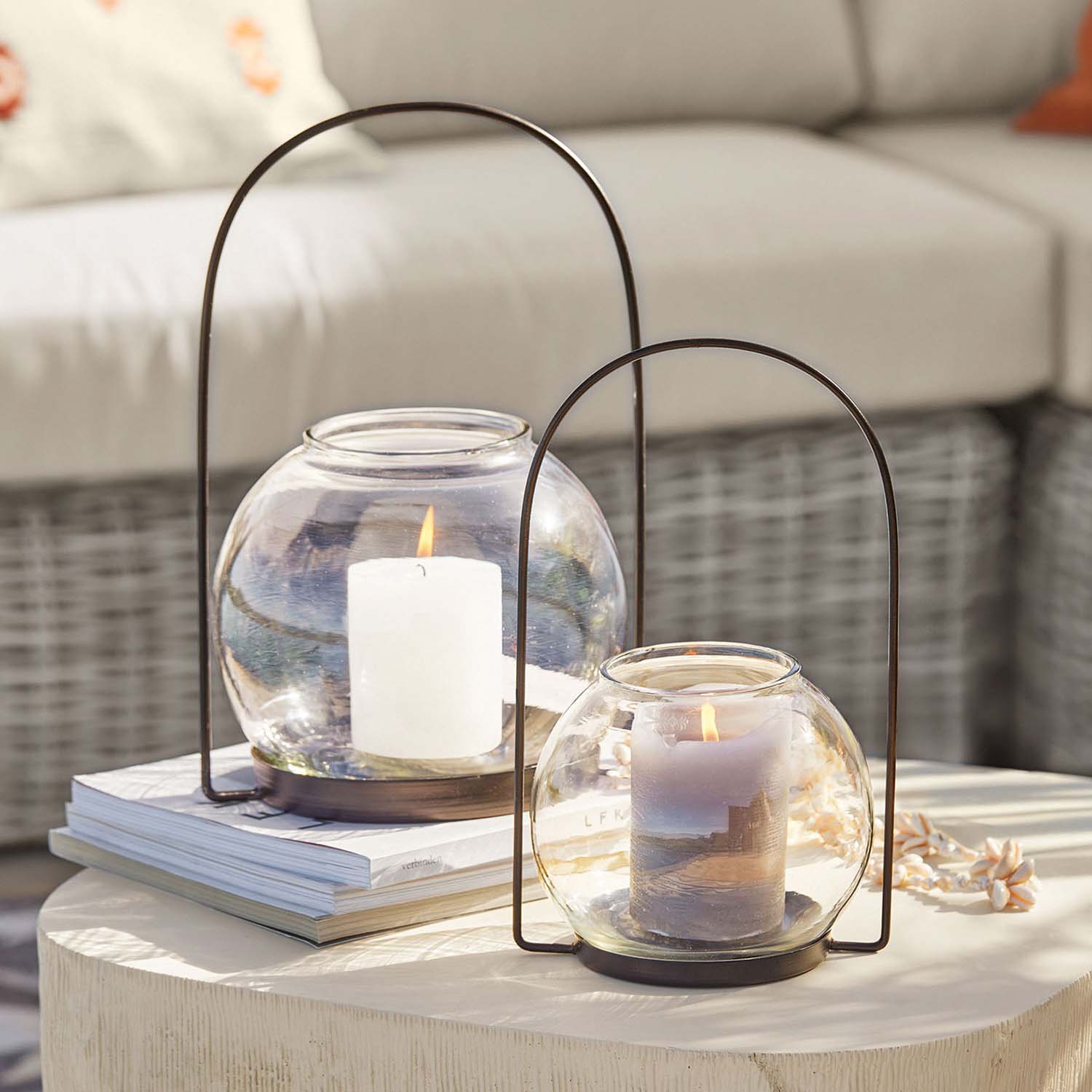 Glaslaternen mit Metallbügeln, weiße und graue Kerzen, stilvolle Tischdekoration im Wohnzimmer