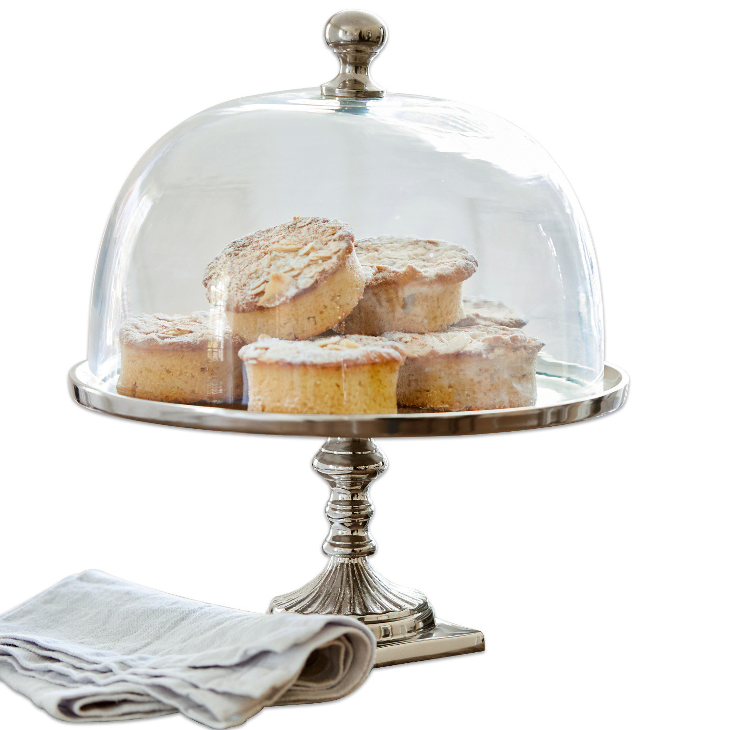 Glasglocke mit Platte Mine Silberner Tortenständer mit glockenförmiger Haube, gefüllt mit kleinen Kuchen und Leinenserviette