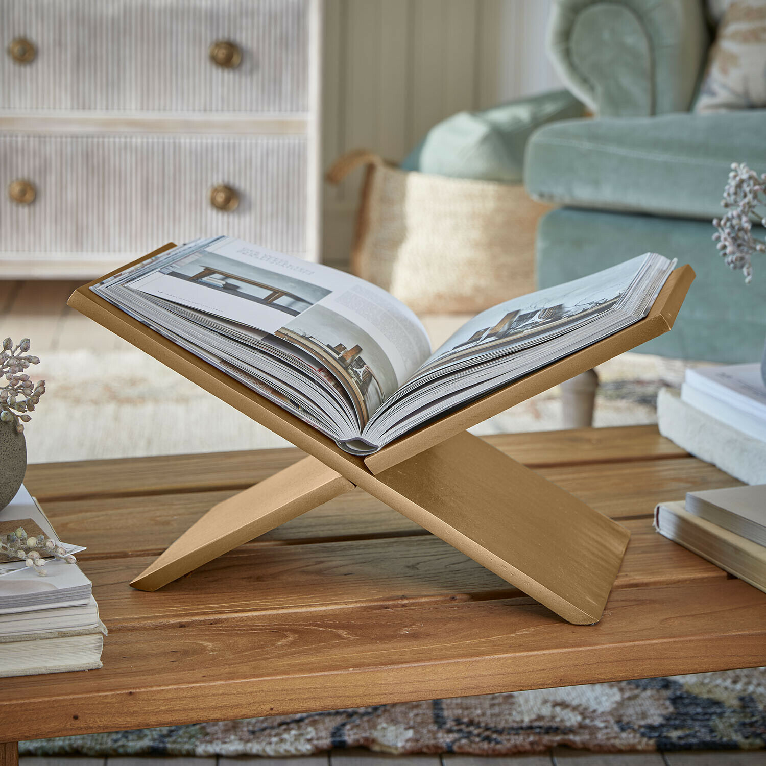 Goldener Holzbuchständer auf Couchtisch in gemütlichem Wohnzimmer mit grünem Sofa