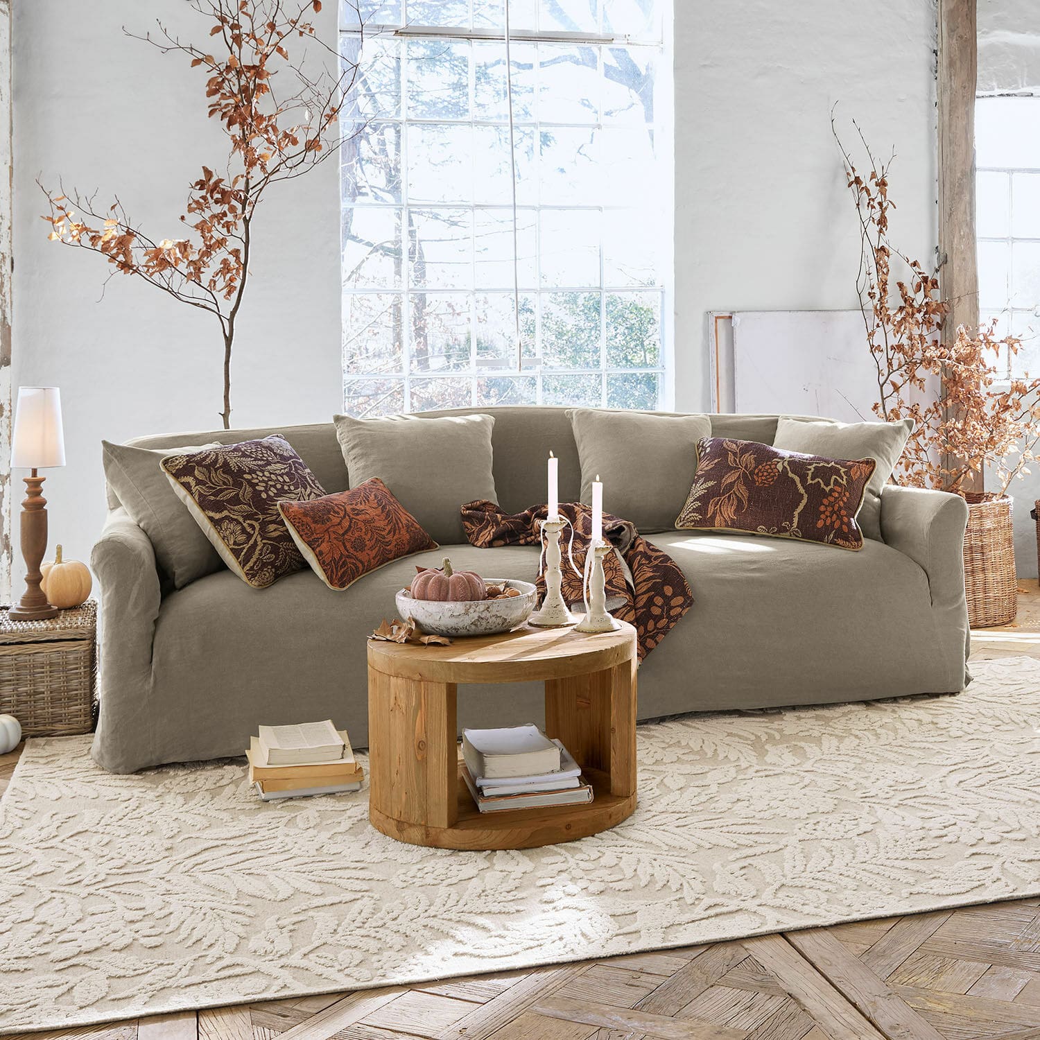 Sofa Riveneuve Beige Stoffsofa in hellem Wohnzimmer mit rundem Holztisch und herbstlicher Dekoration