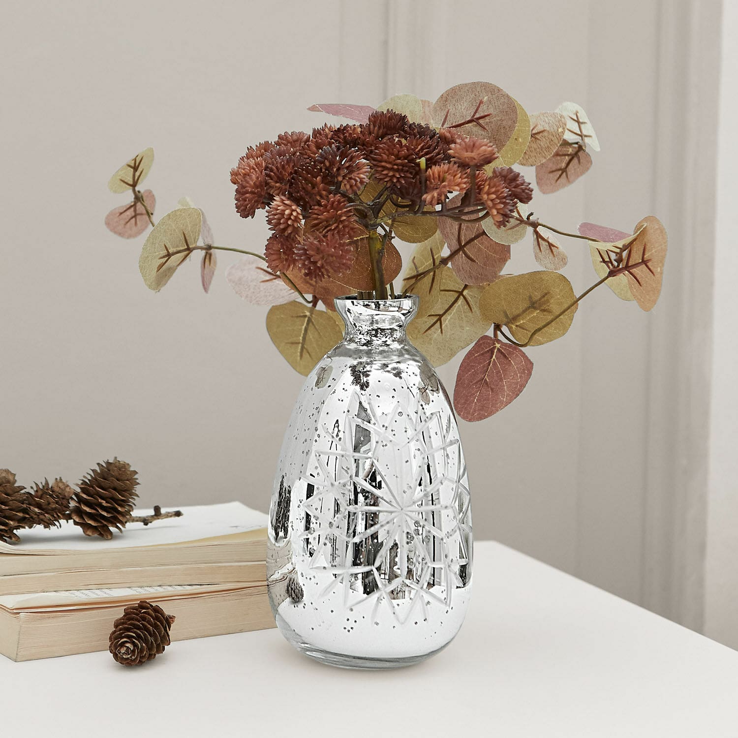 Vase Zorelie Silberne Glasvase mit graviertem Muster und getrockneten braunen Blumen auf weißem Tisch