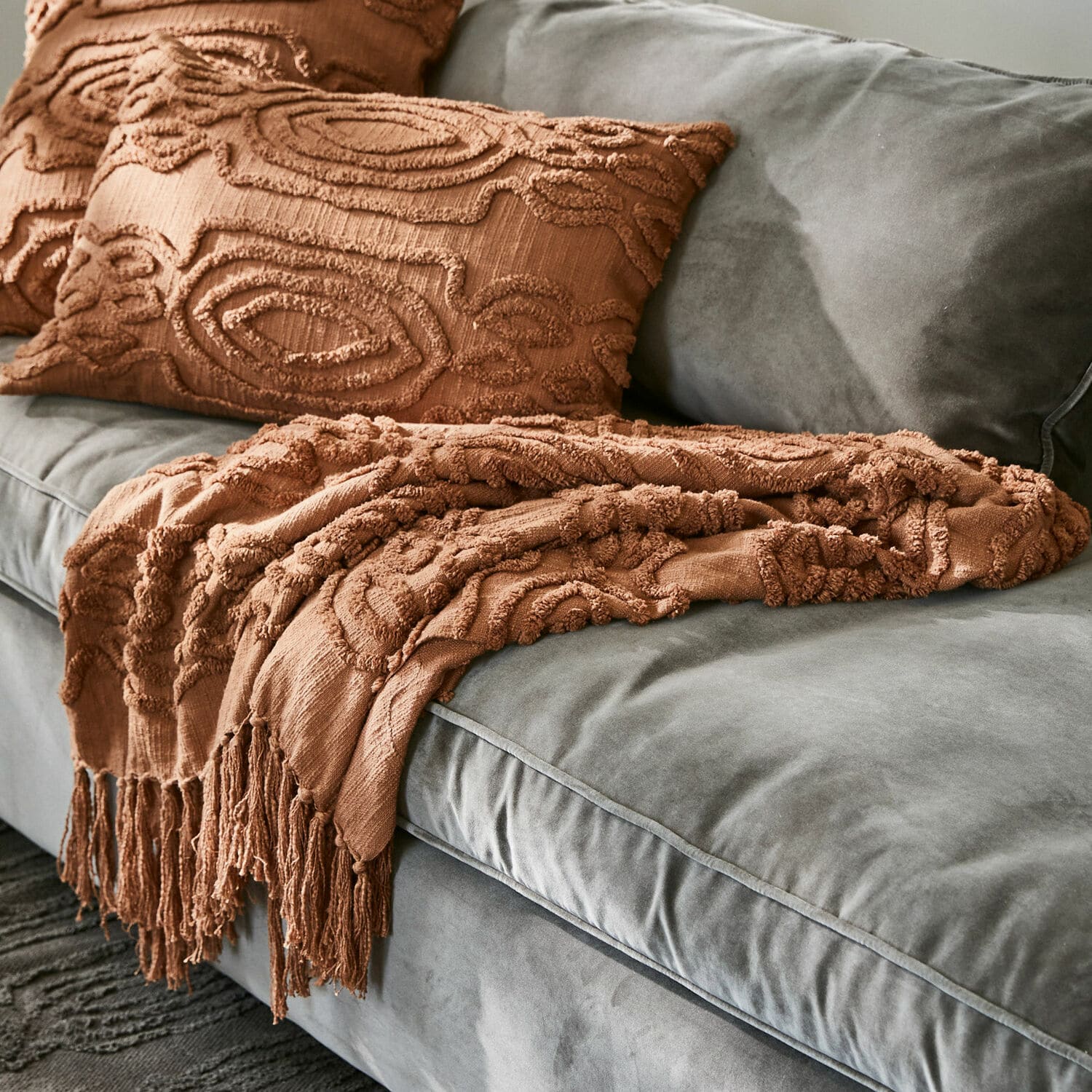 Plaid Boclour Braune dekorative Decke und Kissen mit Struktur auf grauem Samtsofa im Wohnzimmer
