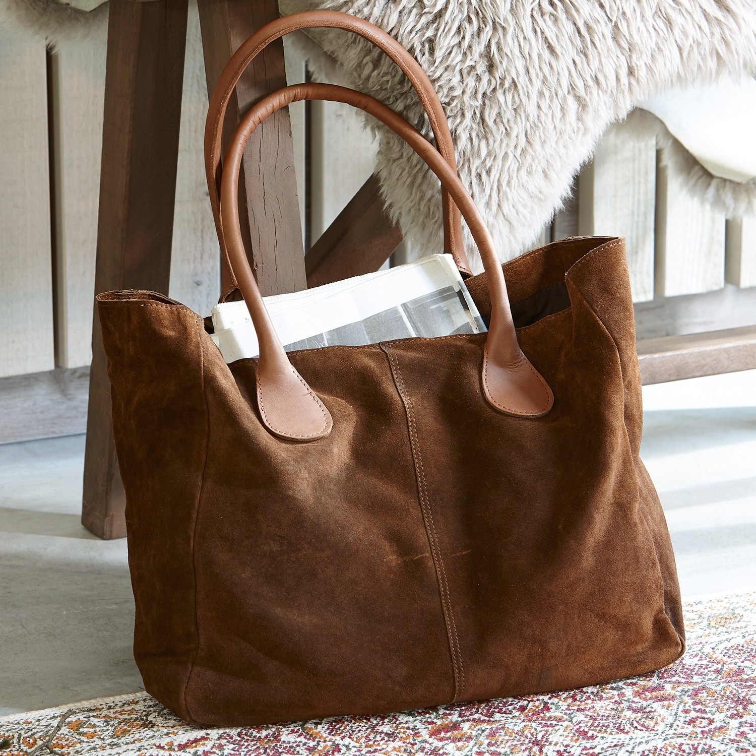Tasche Genevielle Braune Wildledertasche mit hellbraunen Ledergriffen auf Teppichboden neben Holzstuhl