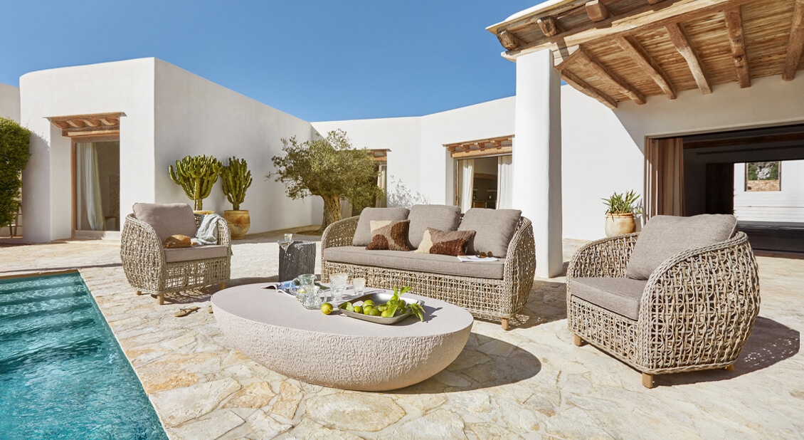 Gartenmöbel-Set aus beigem Rattan mit grauen Kissen am Pool auf steinerner Terrasse