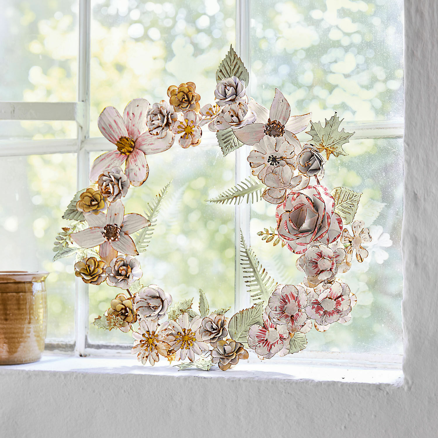 Dekorativer Metallblumenkranz in Pastellfarben am Fenster, stilvolle Wohnraumdekoration