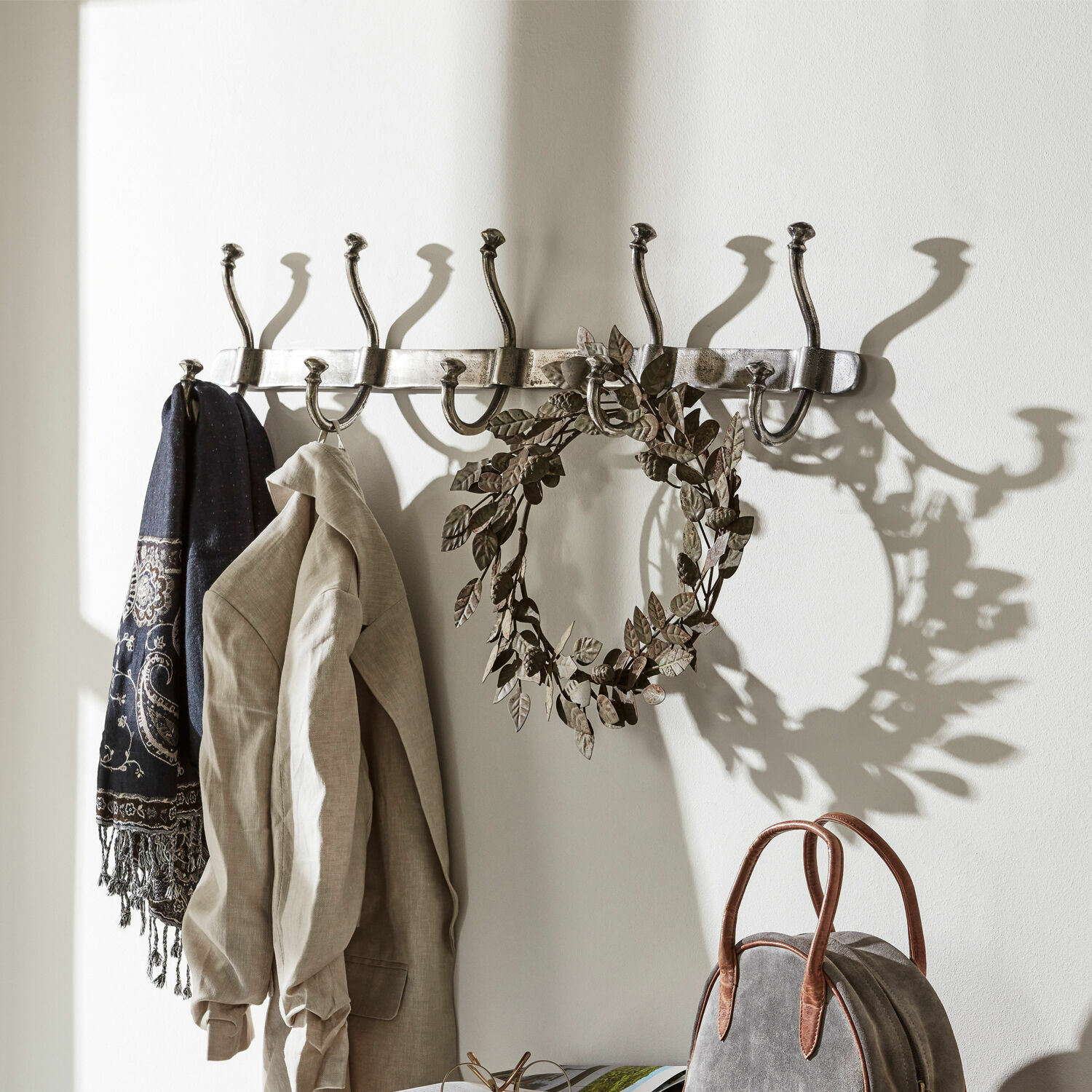 Hakenleiste Pincé Wandgarderobe aus Metall mit acht silbernen Haken, an denen Jacke und Schal hängen