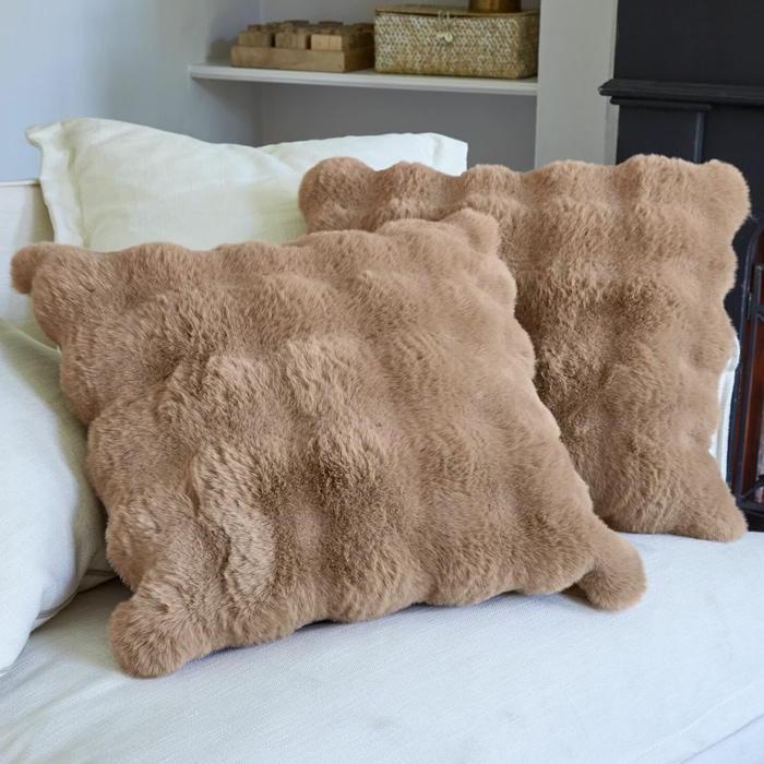 Weiche beige Kissen aus Fellmaterial auf hellem Sofa, gemütliche Wohnraumdekoration