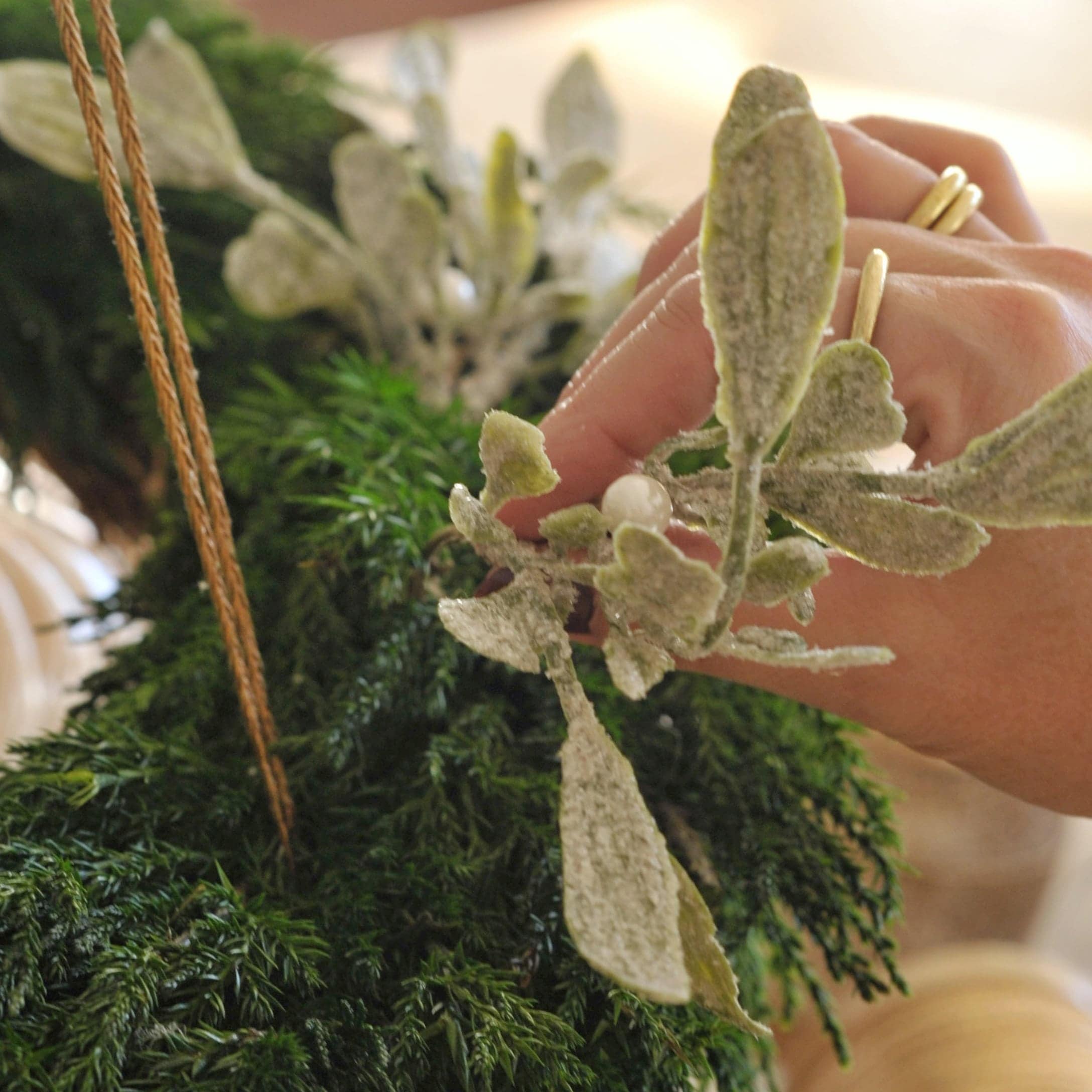 Hand dekoriert weißen Adventskranz mit grünen und weißen Blättern sowie Perlenornamenten
