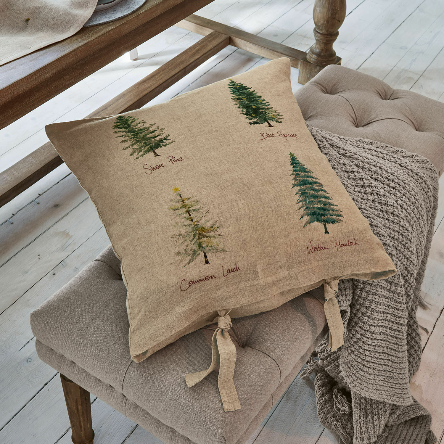 Kissenhülle Jarrier Beige Leinenkissen mit Baumdruck und gebundenen Bändern auf grauem Sitzpolster