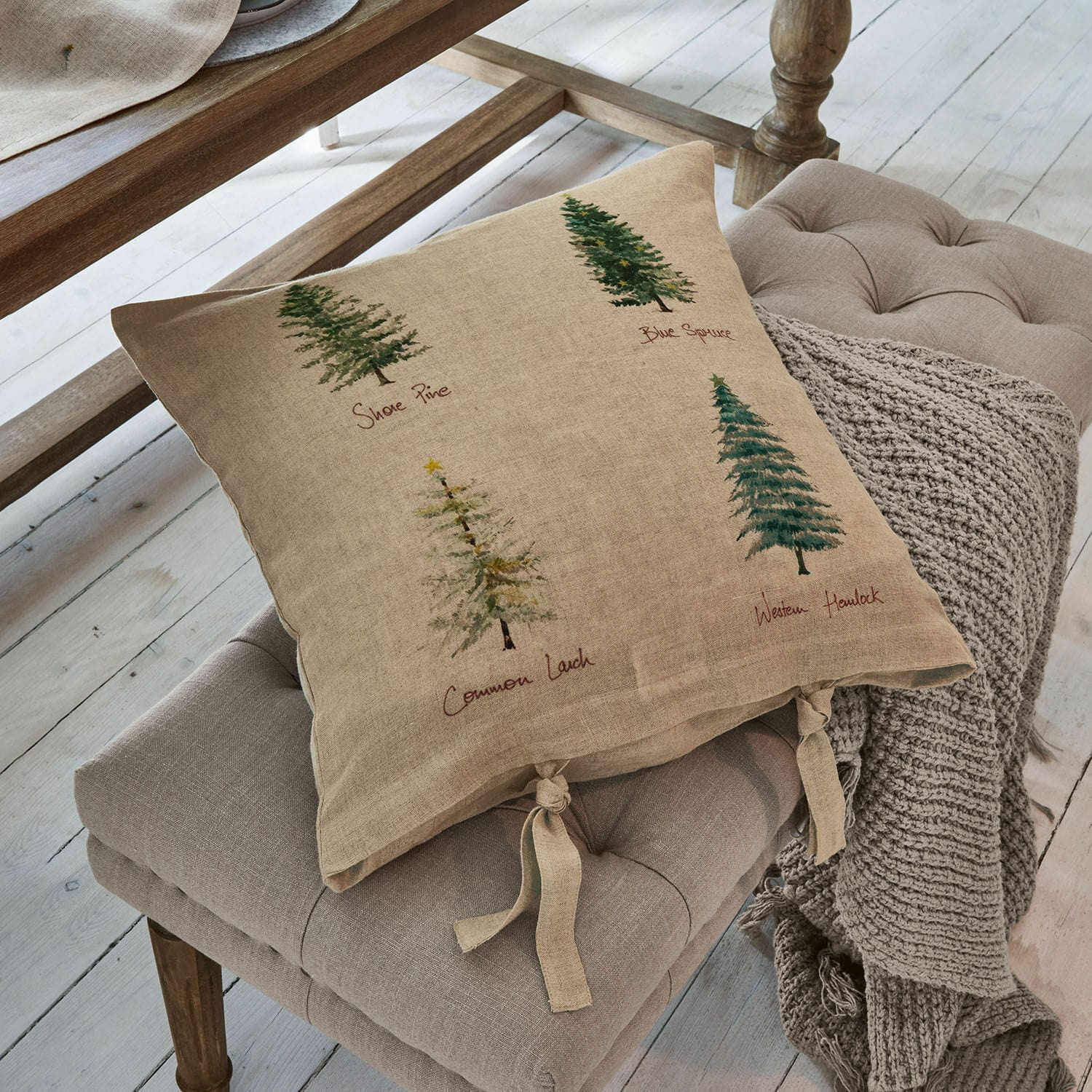 Kissenhülle Jarrier Beige Leinenkissen mit Baumdruck und gebundenen Bändern auf grauem Sitzpolster