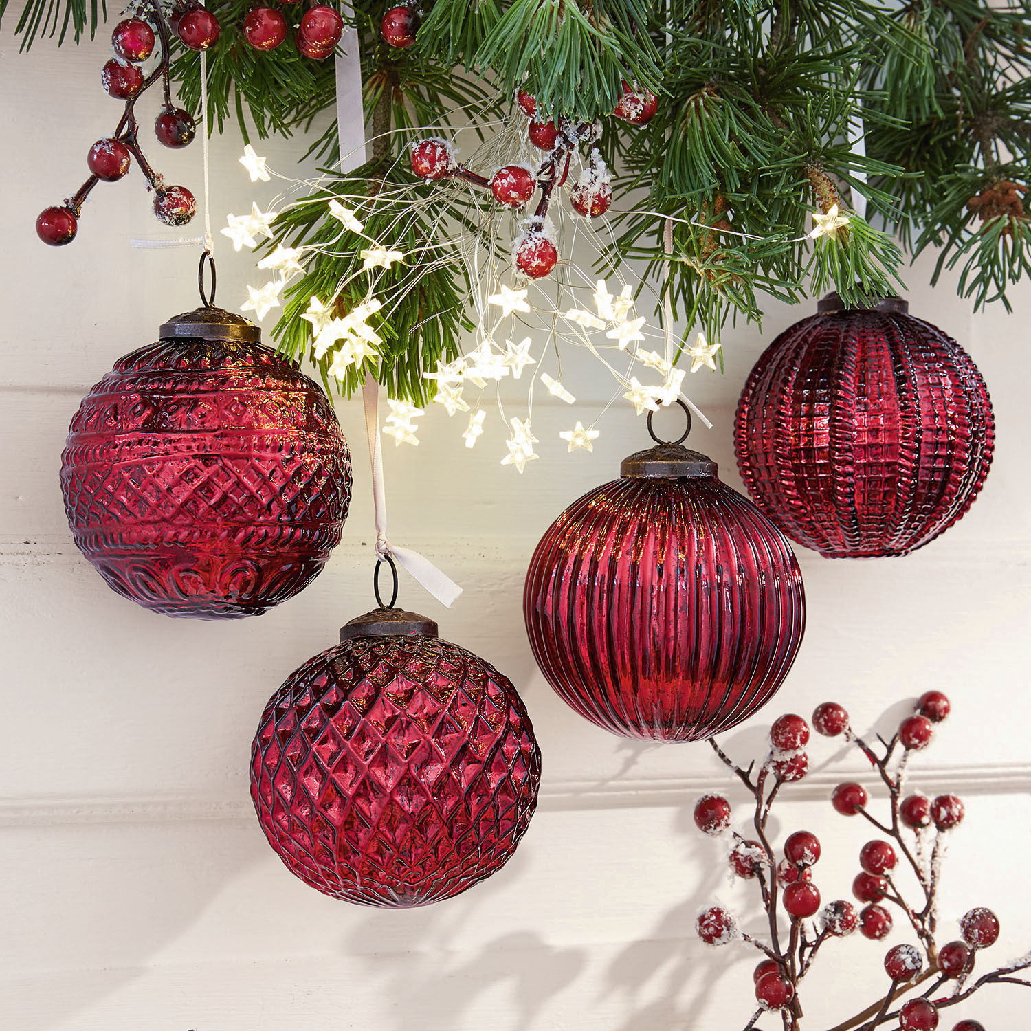 Weihnachtsschmuck 4er Set Ringas Rote Christbaumkugeln aus Glas mit verschiedenen Strukturen und Sternlichterkette an grünen Zweigen