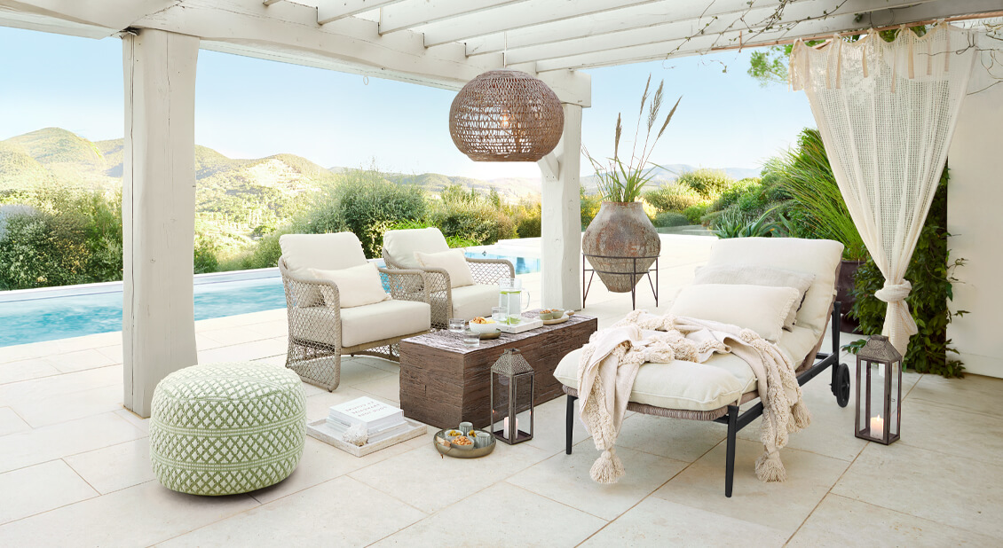 Weißes Gartenmöbel-Set mit Polstern unter Pergola am Pool, natürliche Dekorationen und Laternen