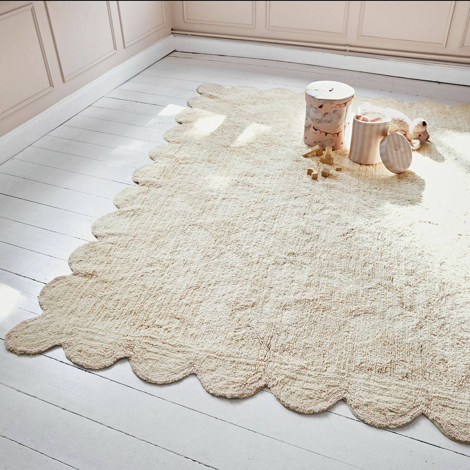 Beiger Teppich aus weichem Material mit wellenförmigem Rand auf hellem Holzboden im Kinderzimmer
