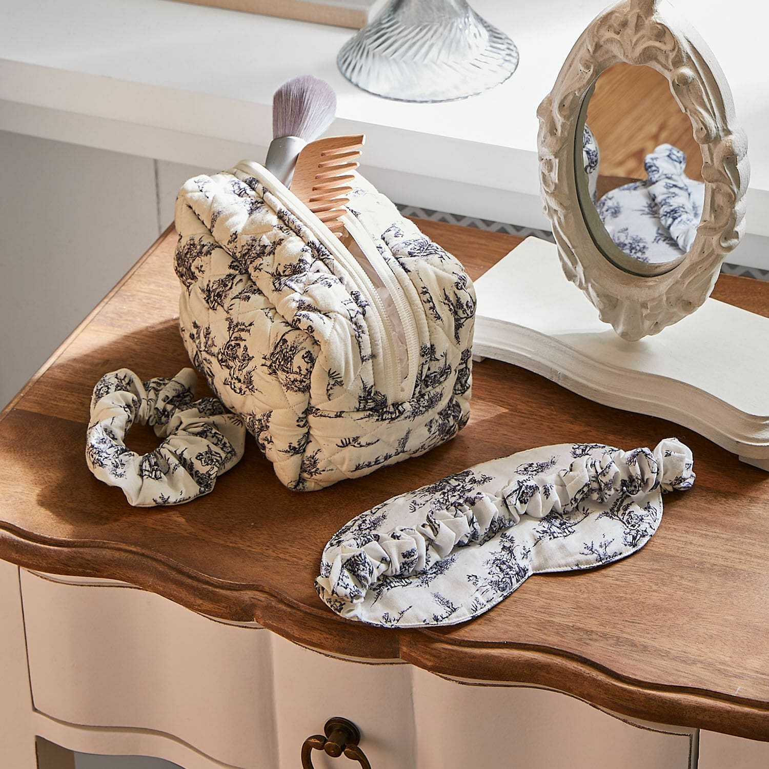 Schlaf-Set 3-teilig Felencio Beige gesteppte Kosmetiktasche mit schwarzem Muster, Haarband und Schlafmaske auf Holzplatte, Pflegeaccessoires