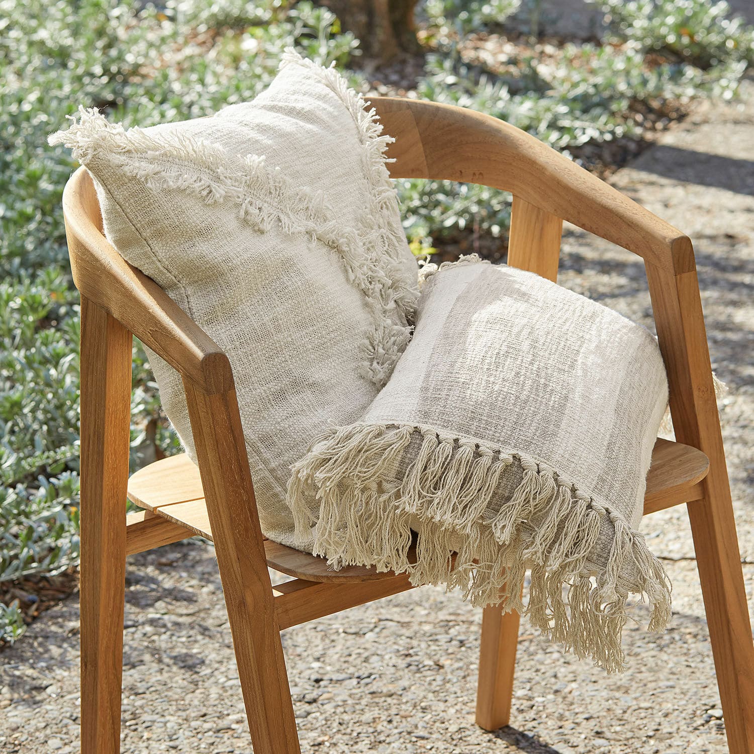 Kissenhülle 2er Set Freya Beige Baumwollkissen und Fransenplaid auf Holzstuhl im Gartenbereich