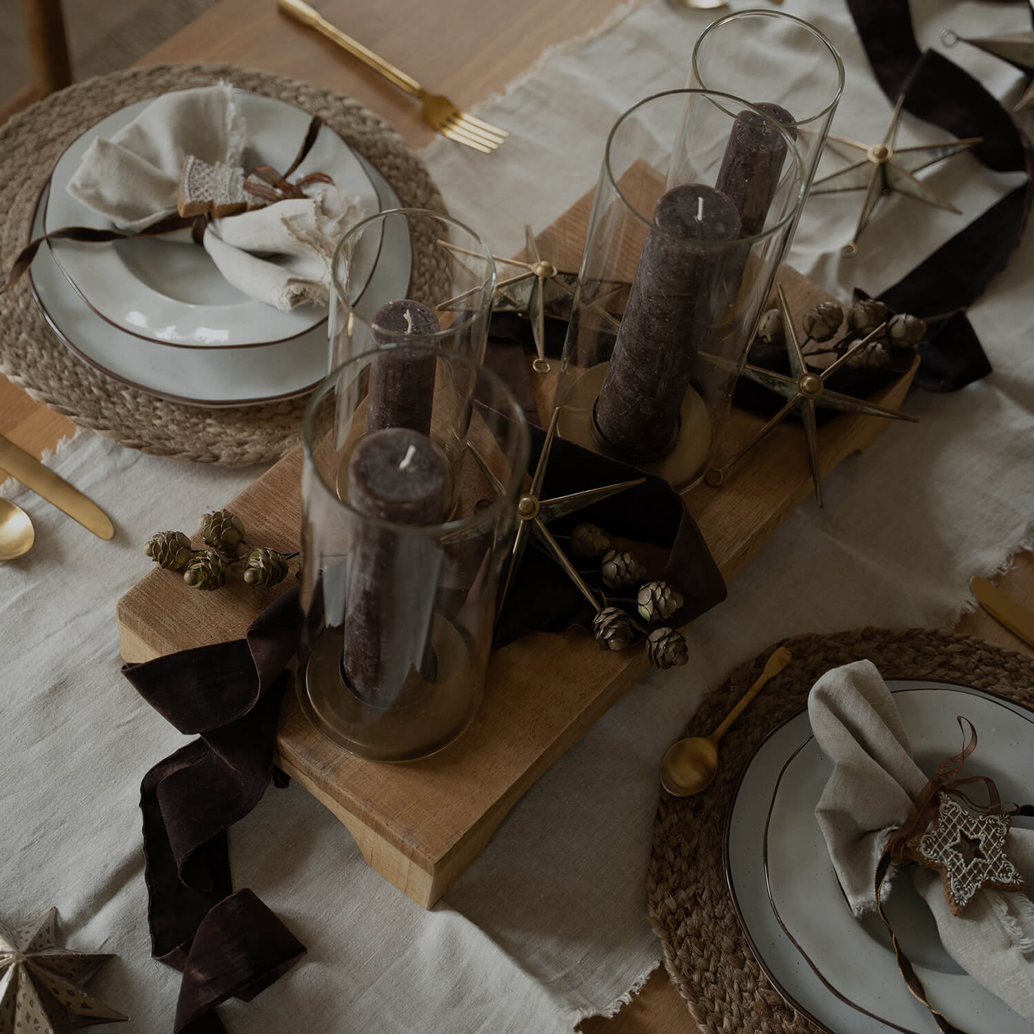 Weihnachtlich dekorierter Tisch mit braunen Kerzen in Glas und natürlichen Deko-Elementen